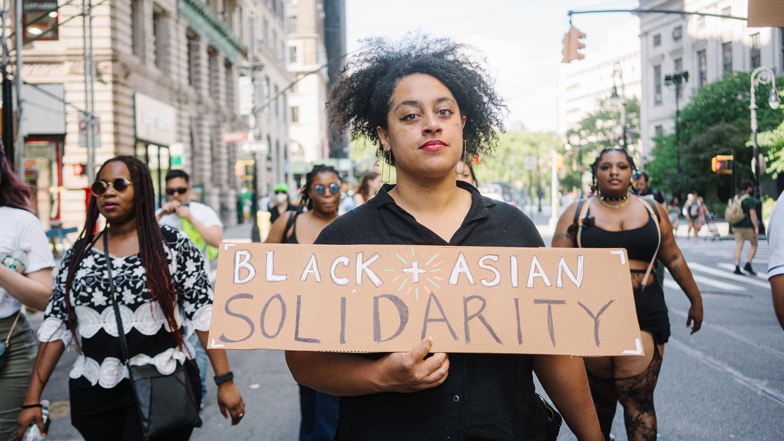 Photo by Cindy Trinh of a person of color holding a sign that says Black Asian Solidarity.