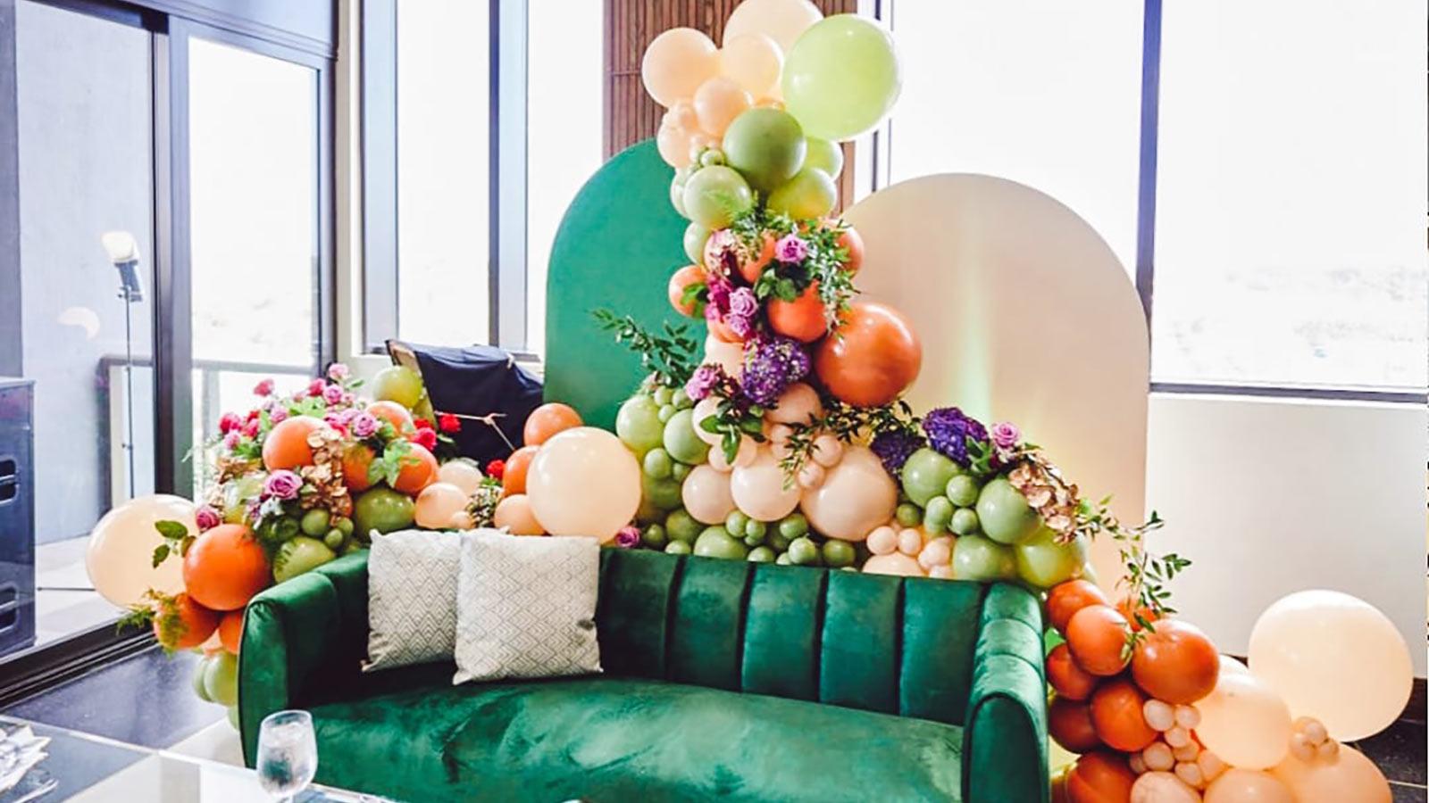 A colorful balloon sculpture designed by a Pace University student surrounds a lush couch.