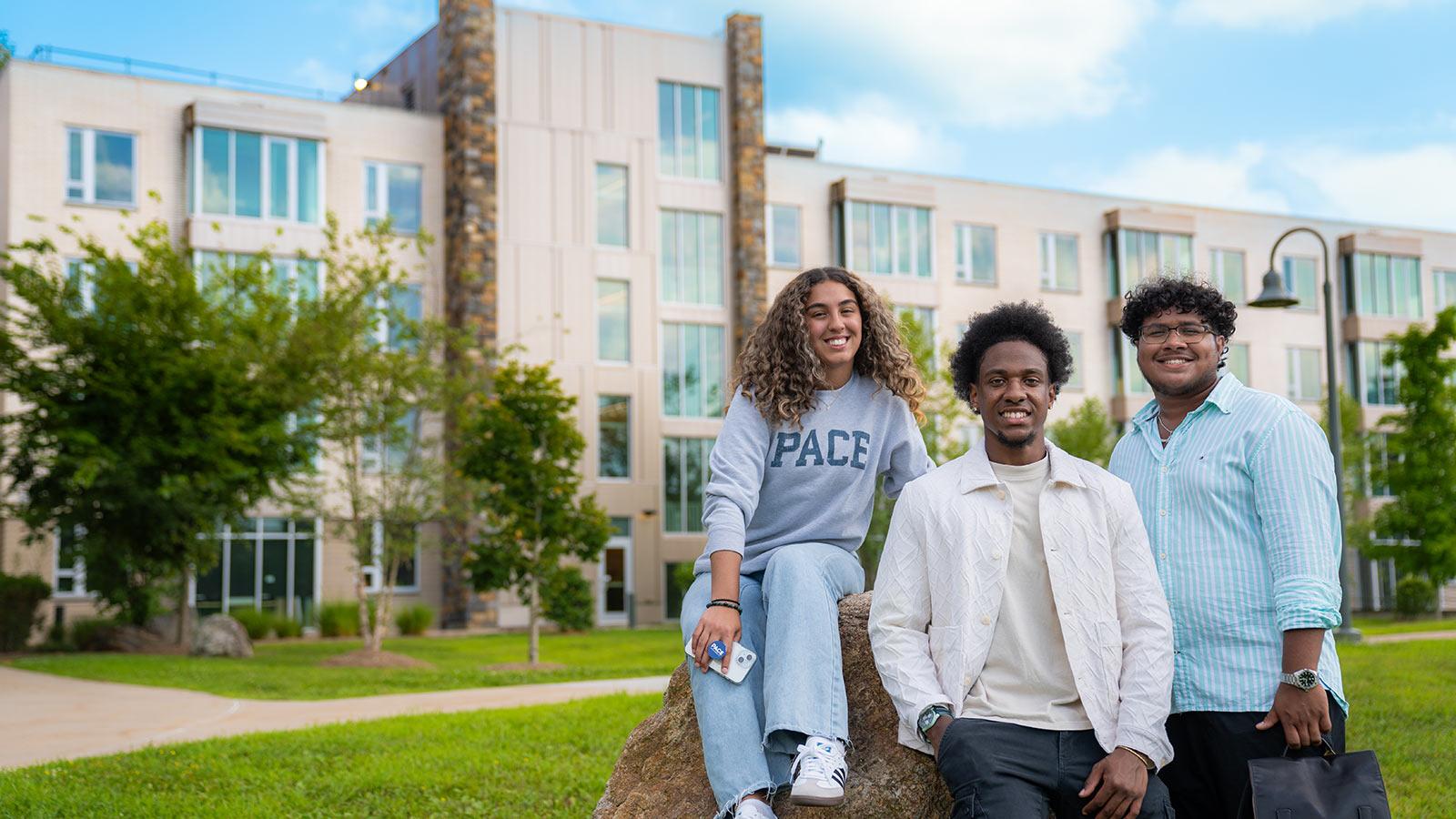 Three students posing for a photo in front of the dorms of the Pace University campus in Pleasantville, NY.
