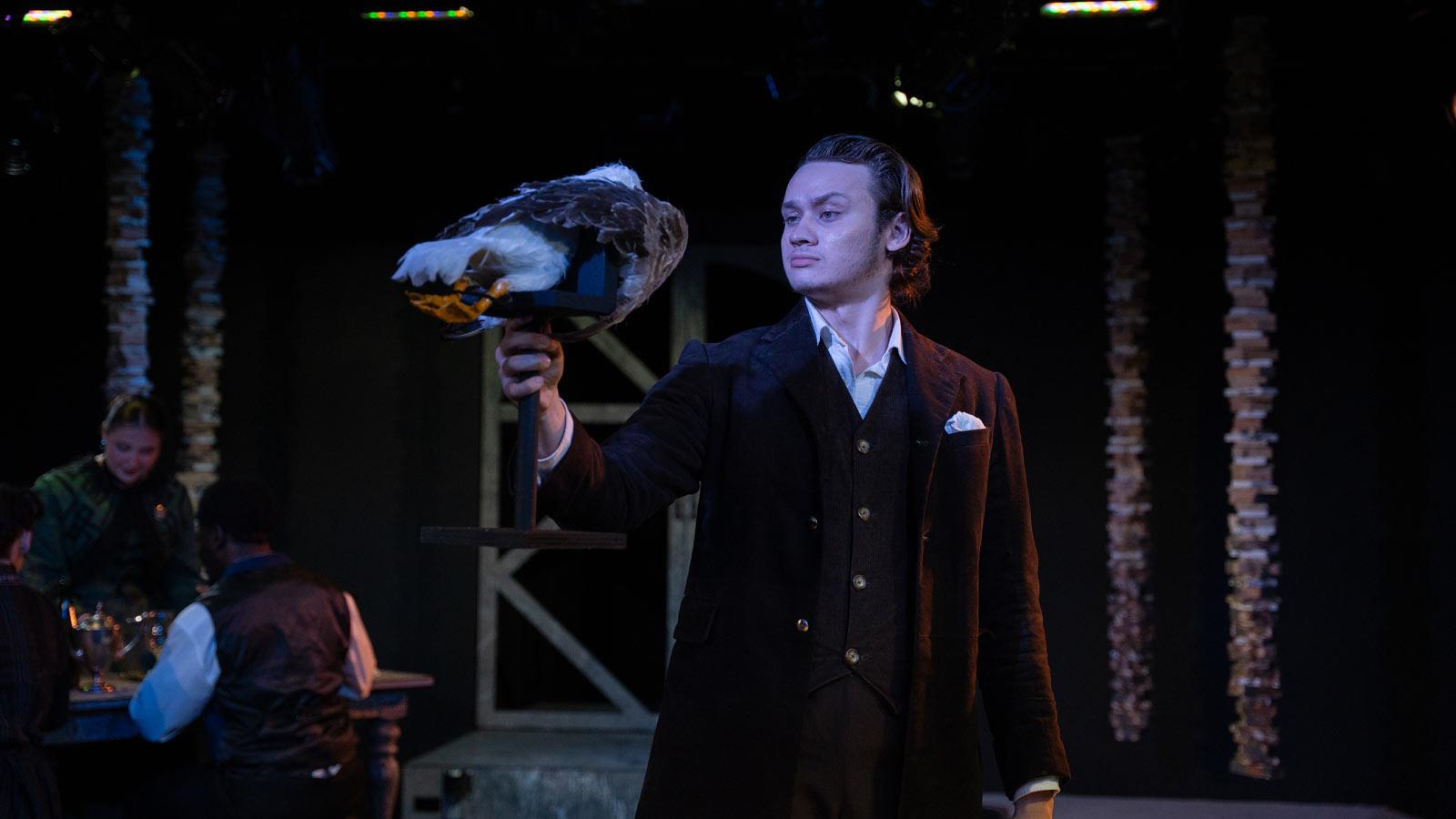 Actor holding a seagull prop on stage.