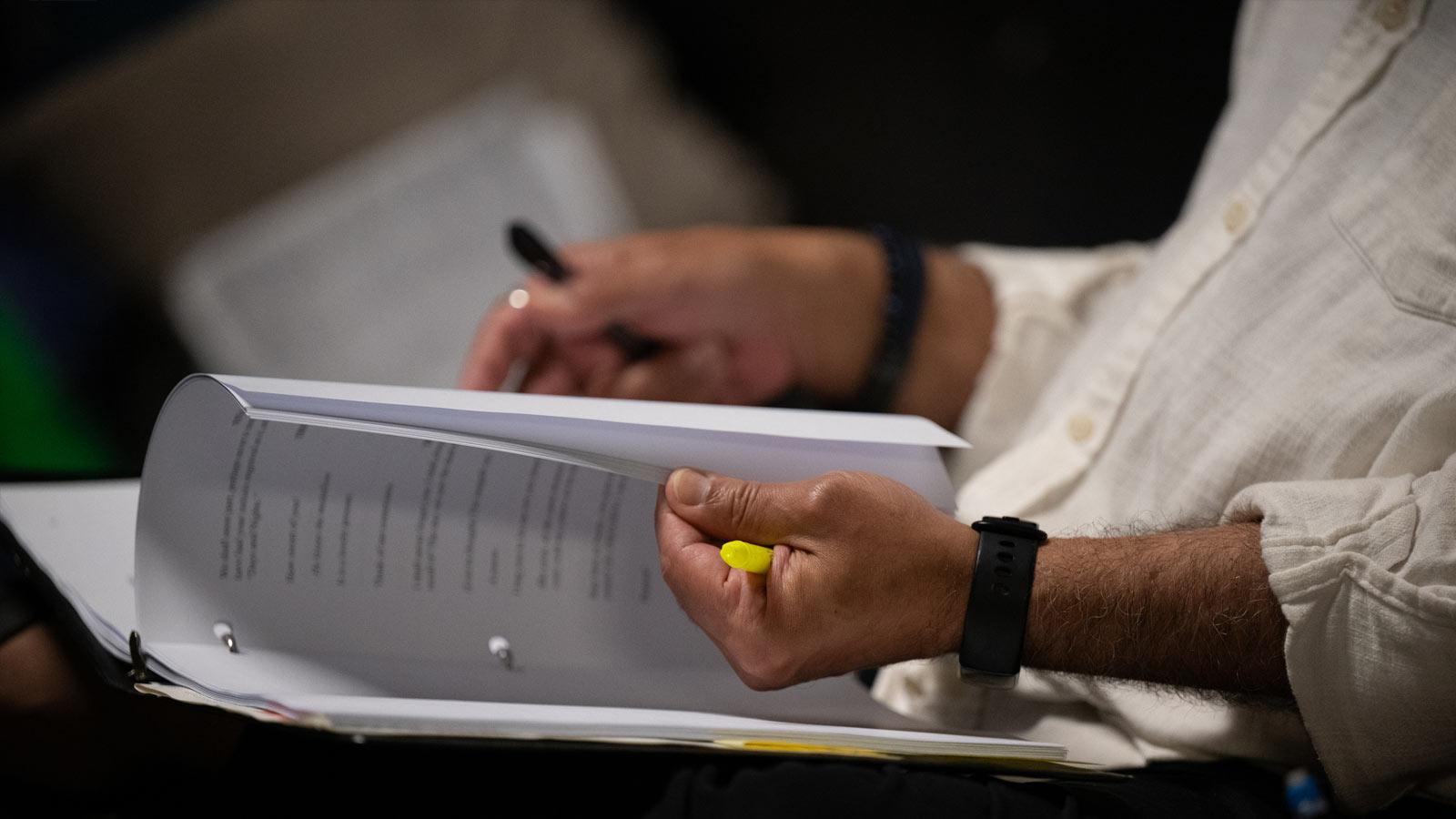 Close-up of hands flipping through a script.