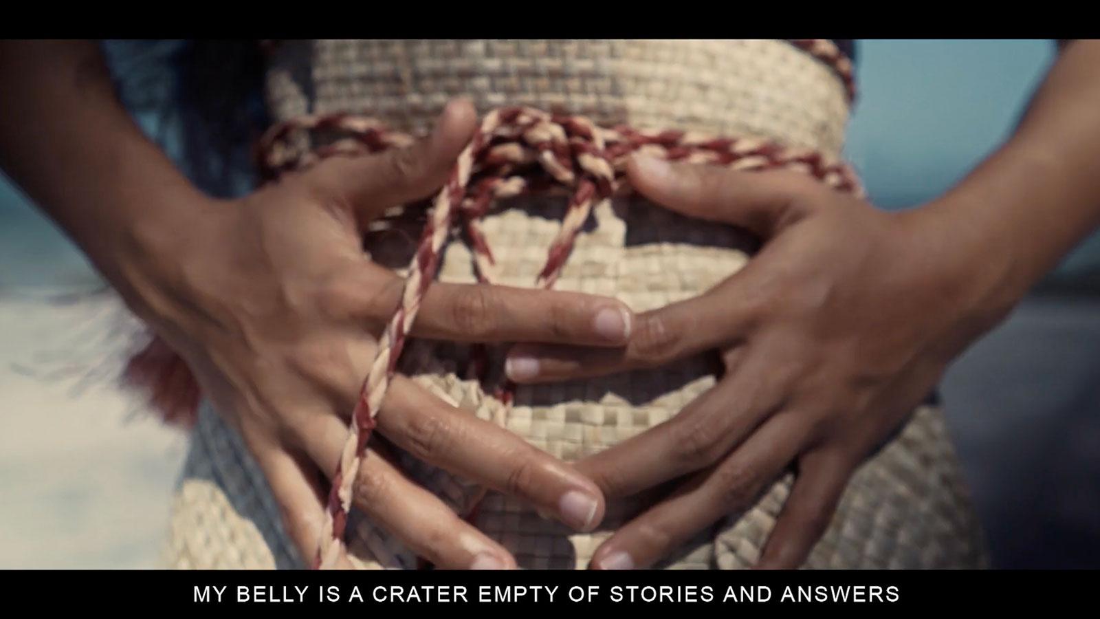 Video still from Annoited film showing a person holding their stomach, on view in the Pace University Art Gallery's Nuclear Injustice exhibition