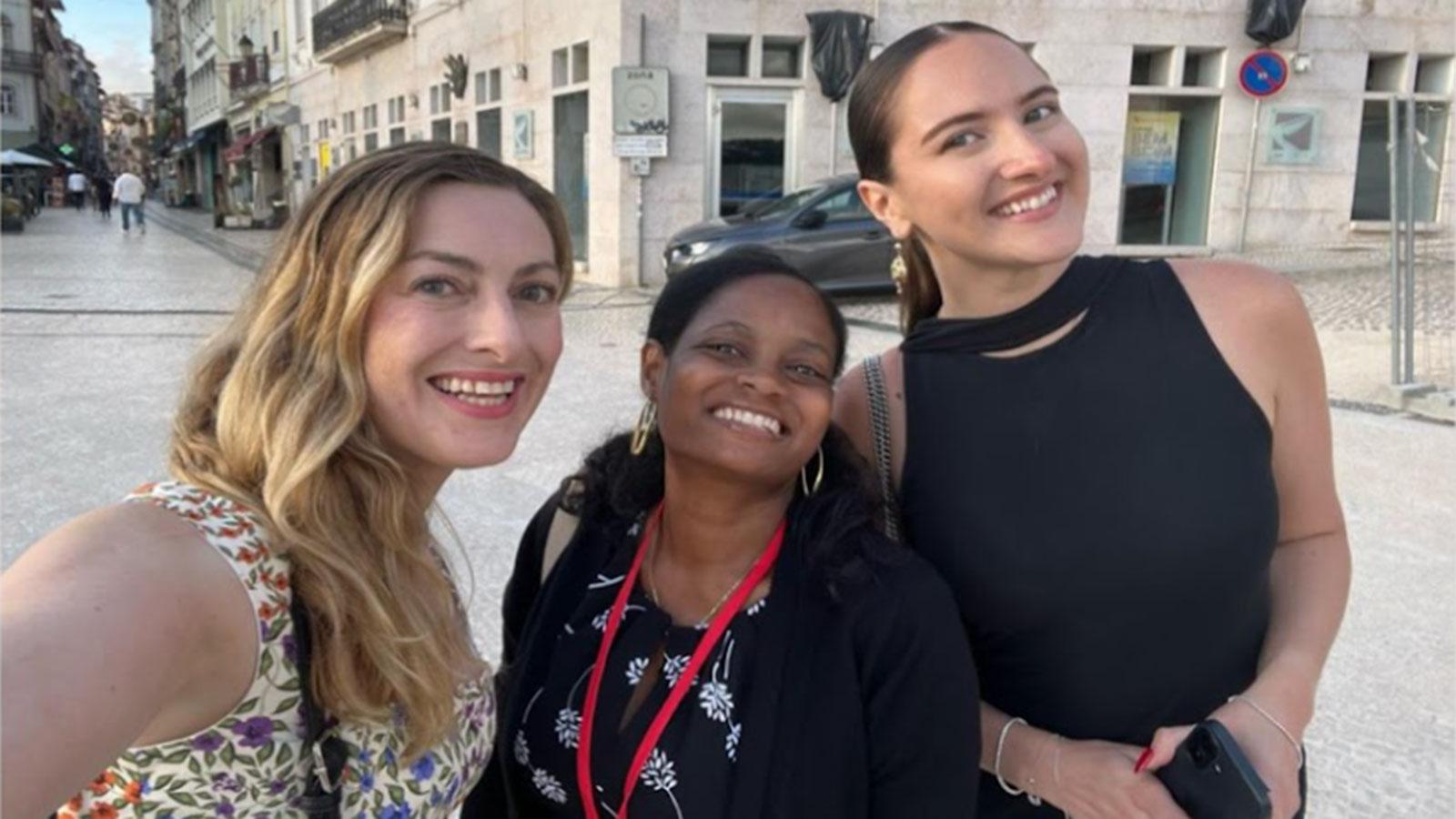 Three Pace University Psychology students standing together, posing in front of a building in Portugal