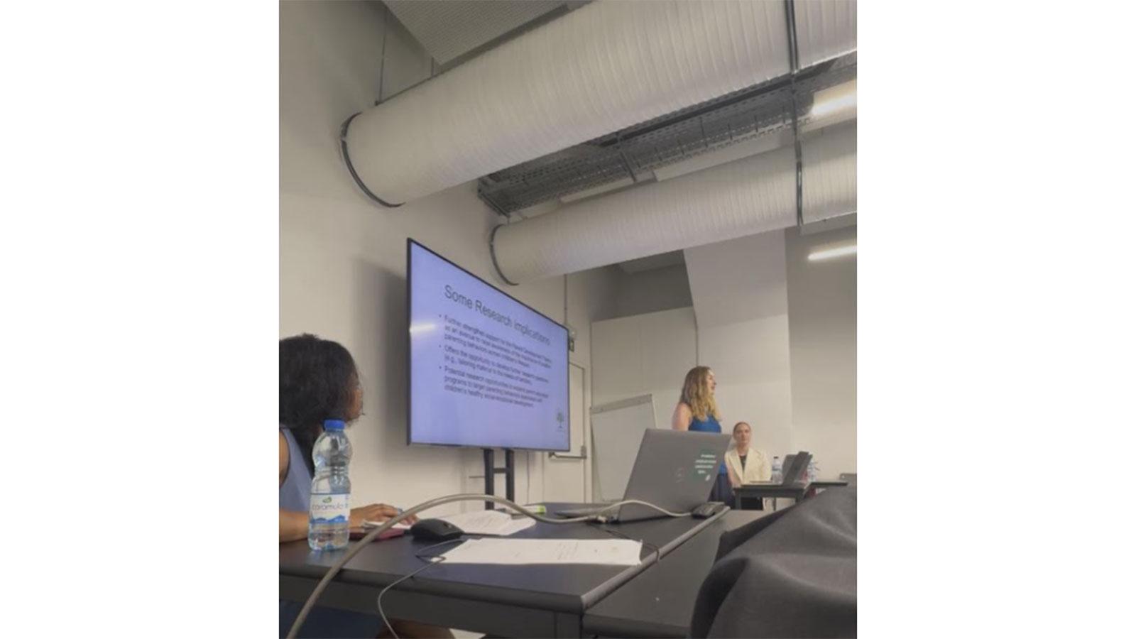 Pace University Psychology student presenting with a screen next to her at a conference