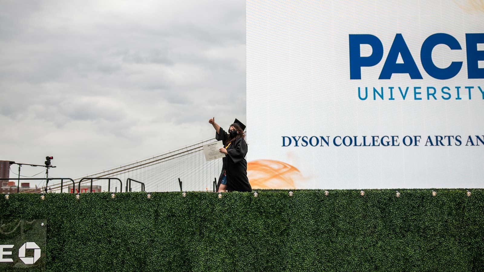 student in academic regalia crossing a stage