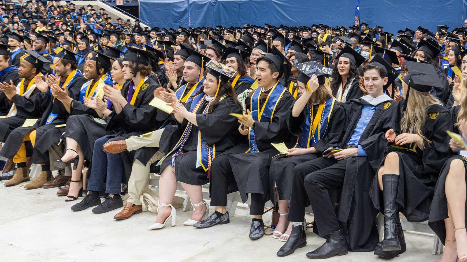Graduates from the Dyson College of Arts and Sciences and the School of Education watch and applaud as Dean Tresmaine R. Grimes, PhD, speaks.  