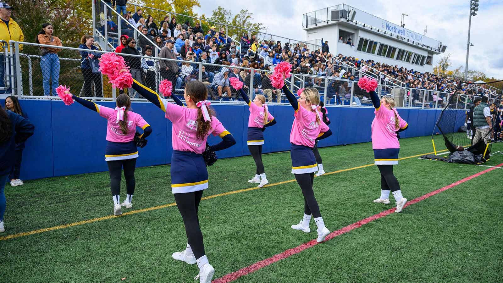 Pace University cheerleaders dancing on the field at Homecoming.