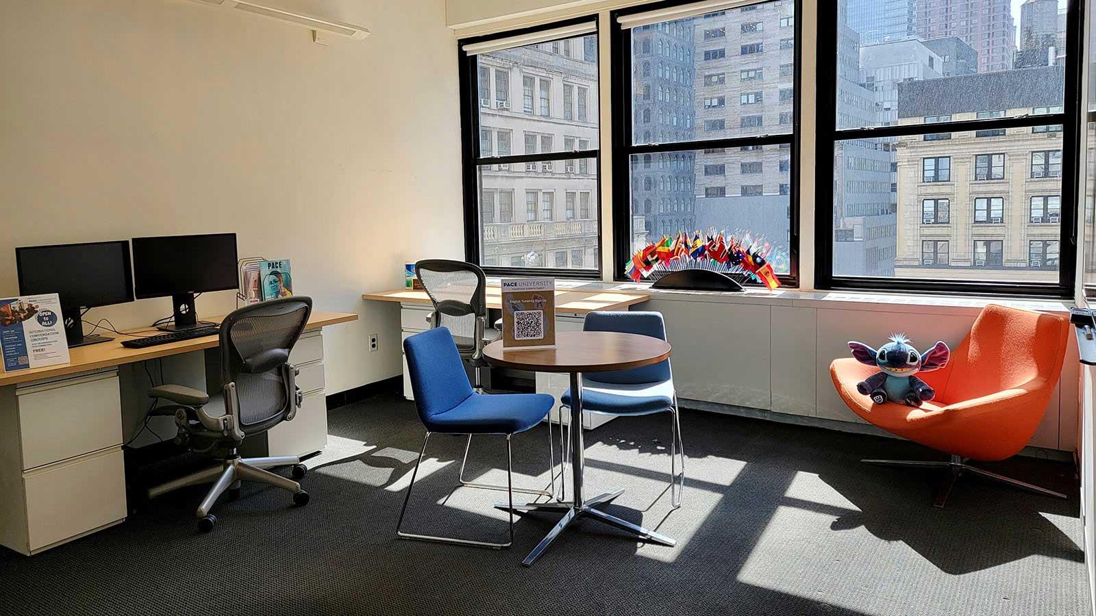 room with a world map on the wall, a desk with a computer, and a table with miniature world flags.