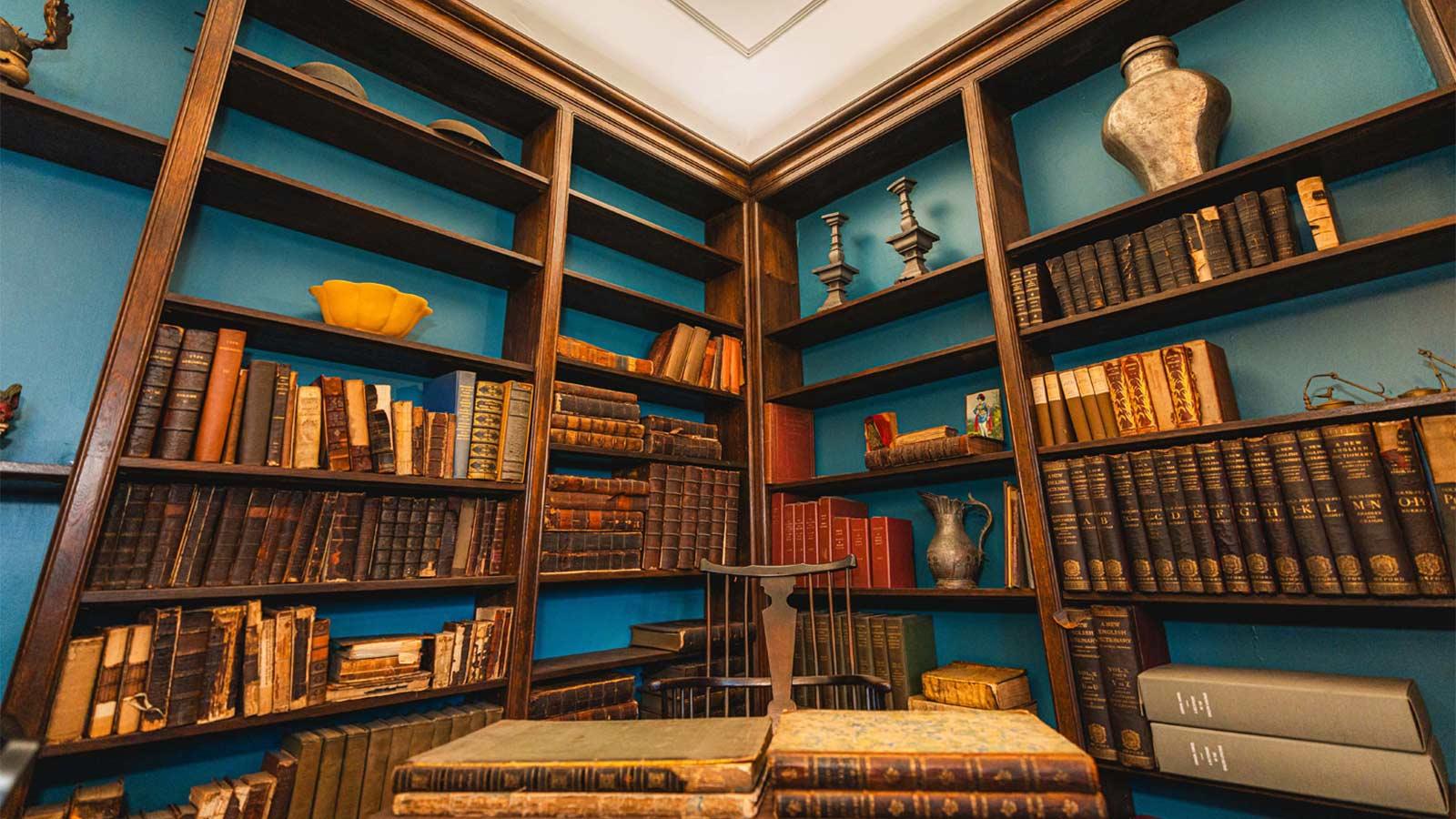 corner of the Pace Study featuring shelving, a desk and chair, and antique knick-knacks. 