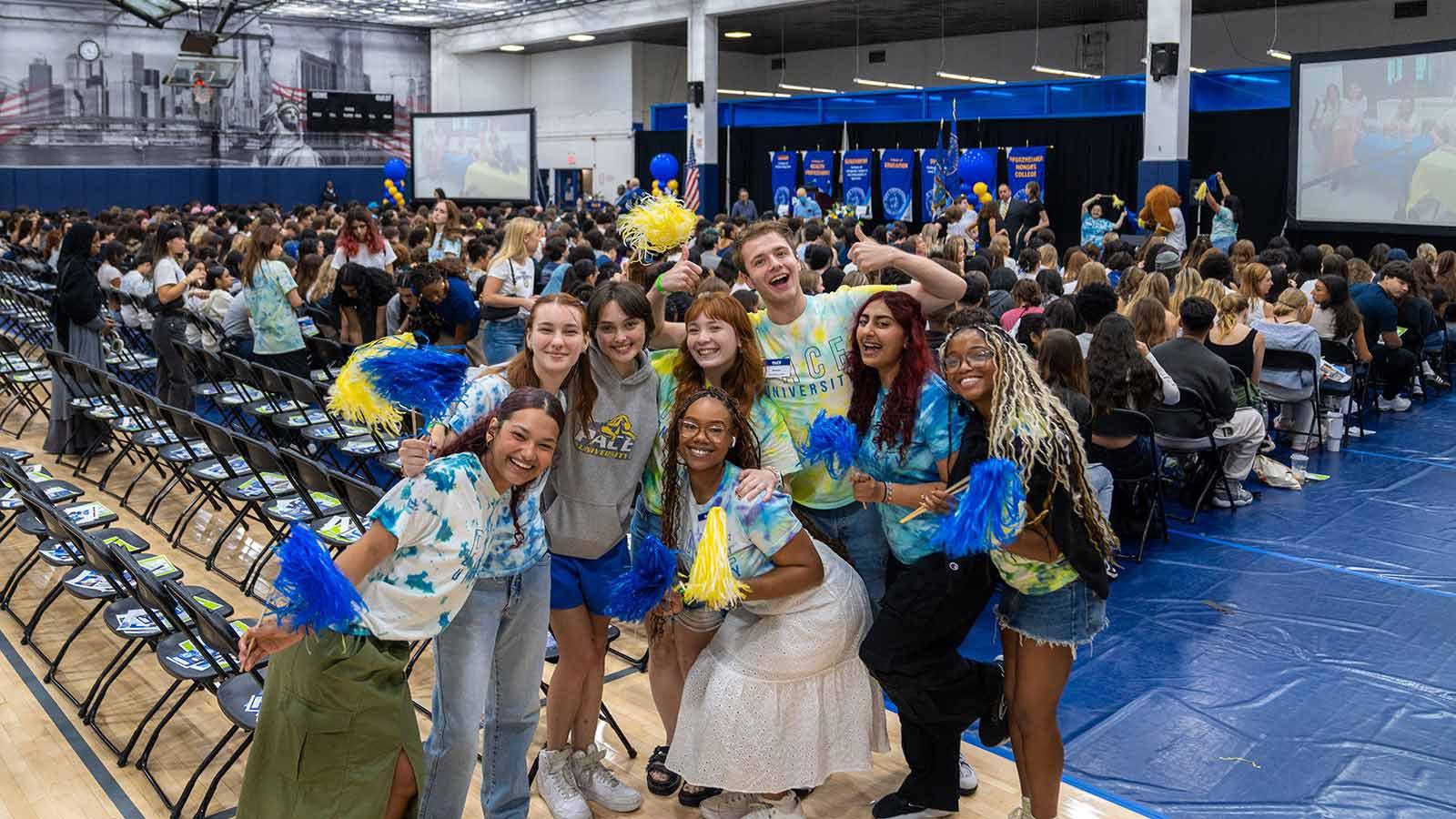 Groups of Pace Students smiling at the camera showing their Pace pride by holding gold and blue pom poms.