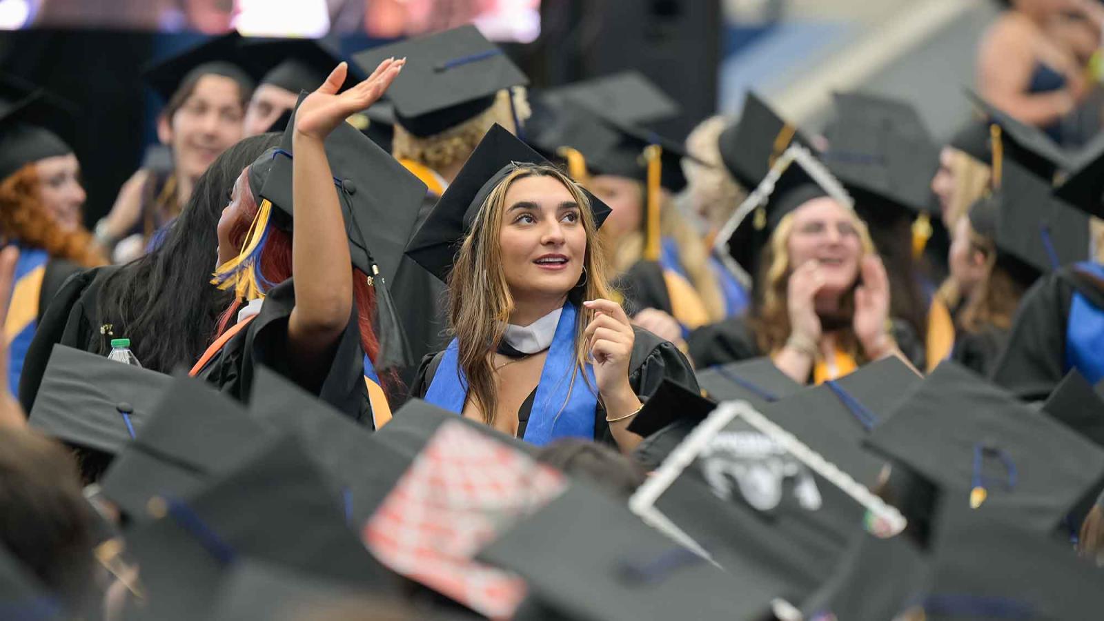 A Pace University graduate student in graduation regalia looks out across the crowd