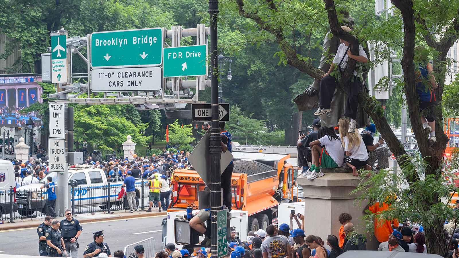Knicks fans climb the iconic Benjamin Franklin statue outside One Pace Plaza