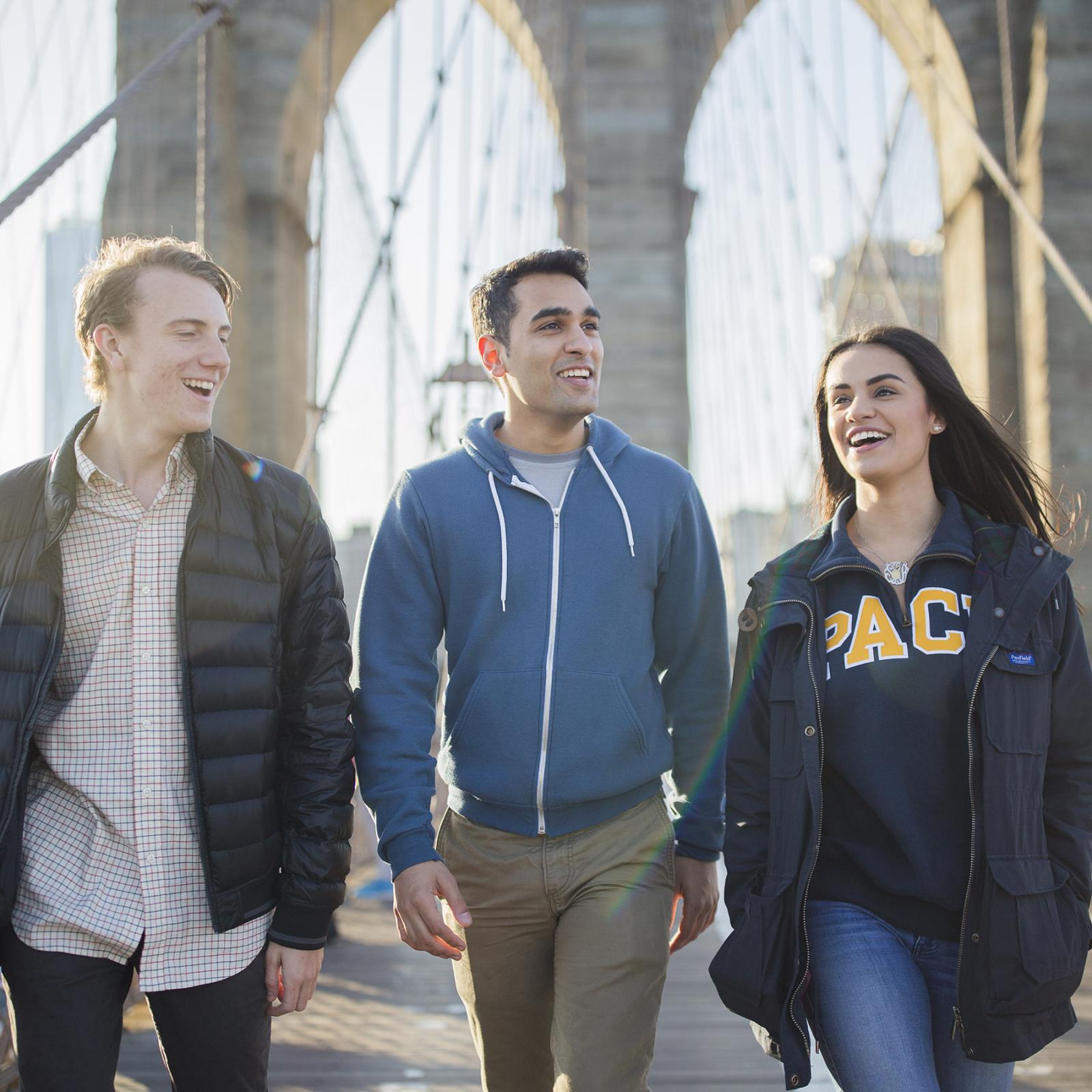 Three Pace Univesity students walking across the Brooklyn Bridge.