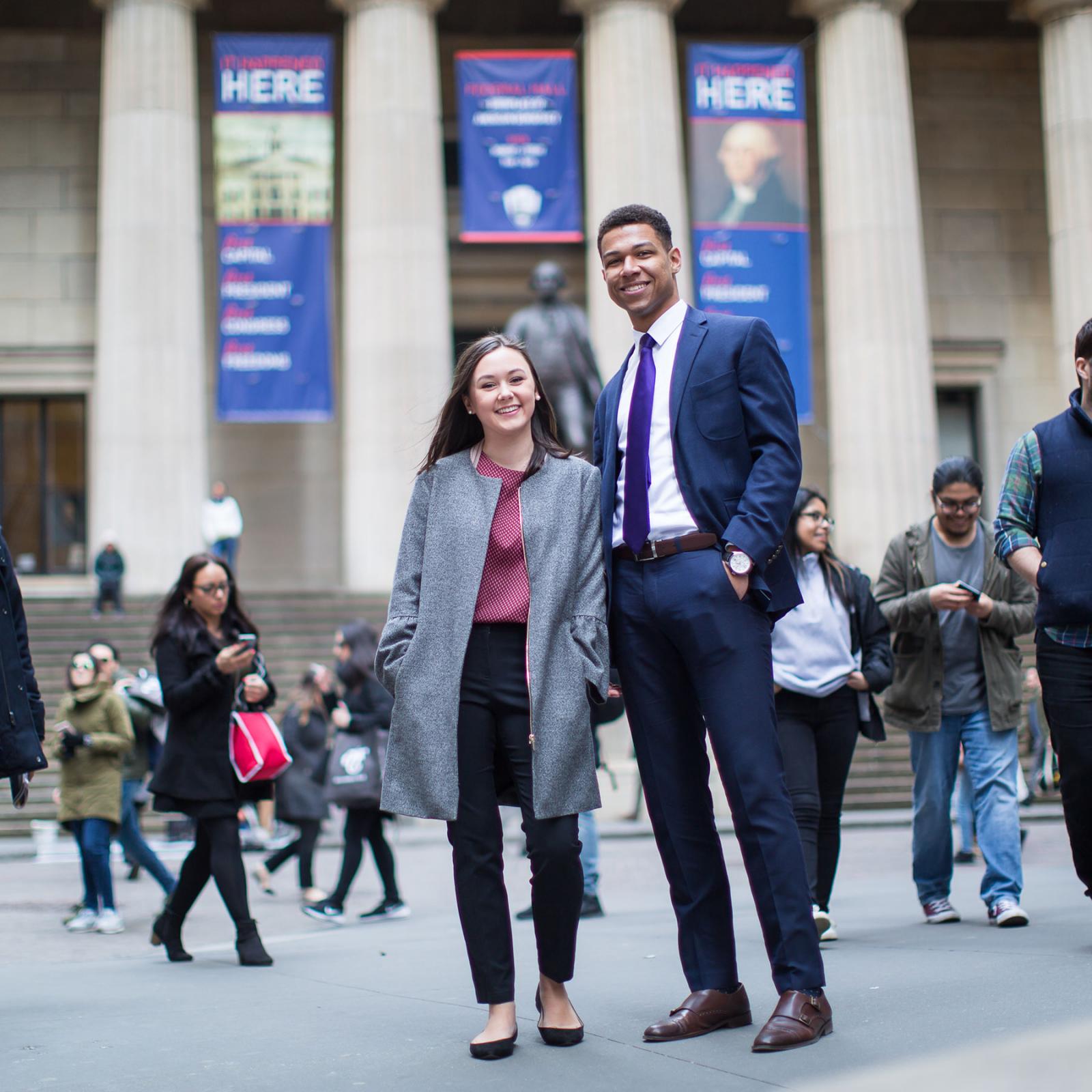 Two people dressed in business attire walking around NYC