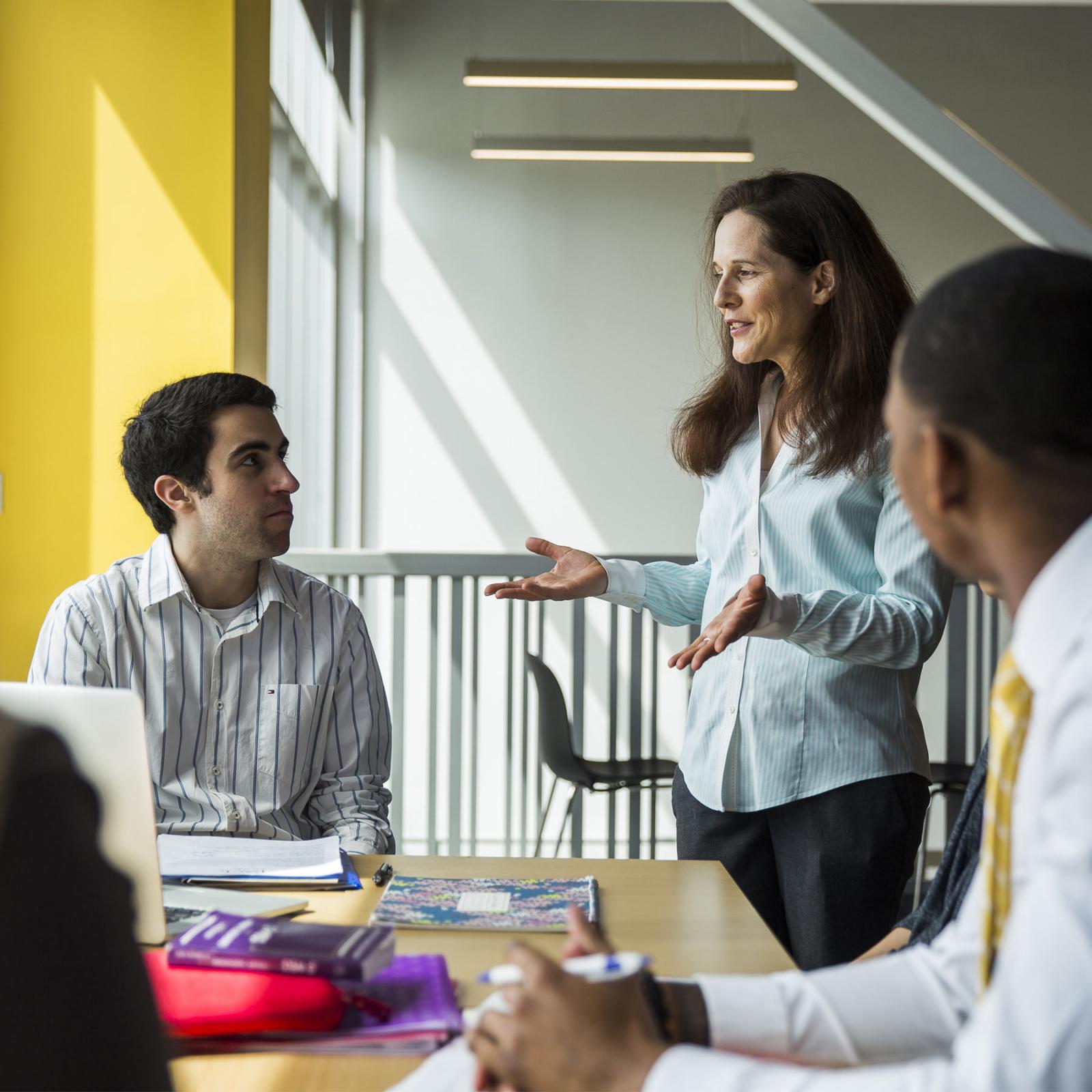 students at a table talking to a faculty member