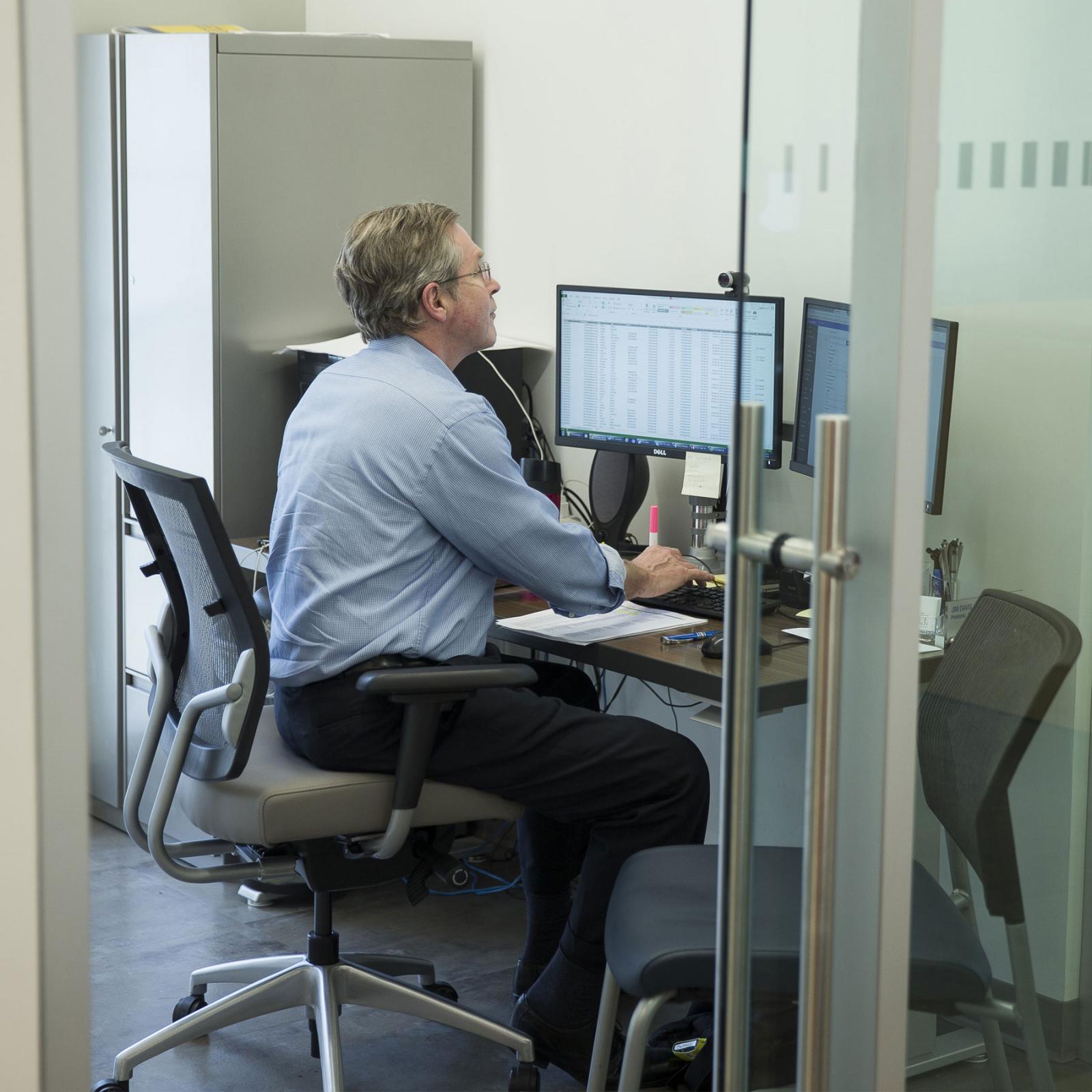 Staff member sitting at his desk working on his computer.