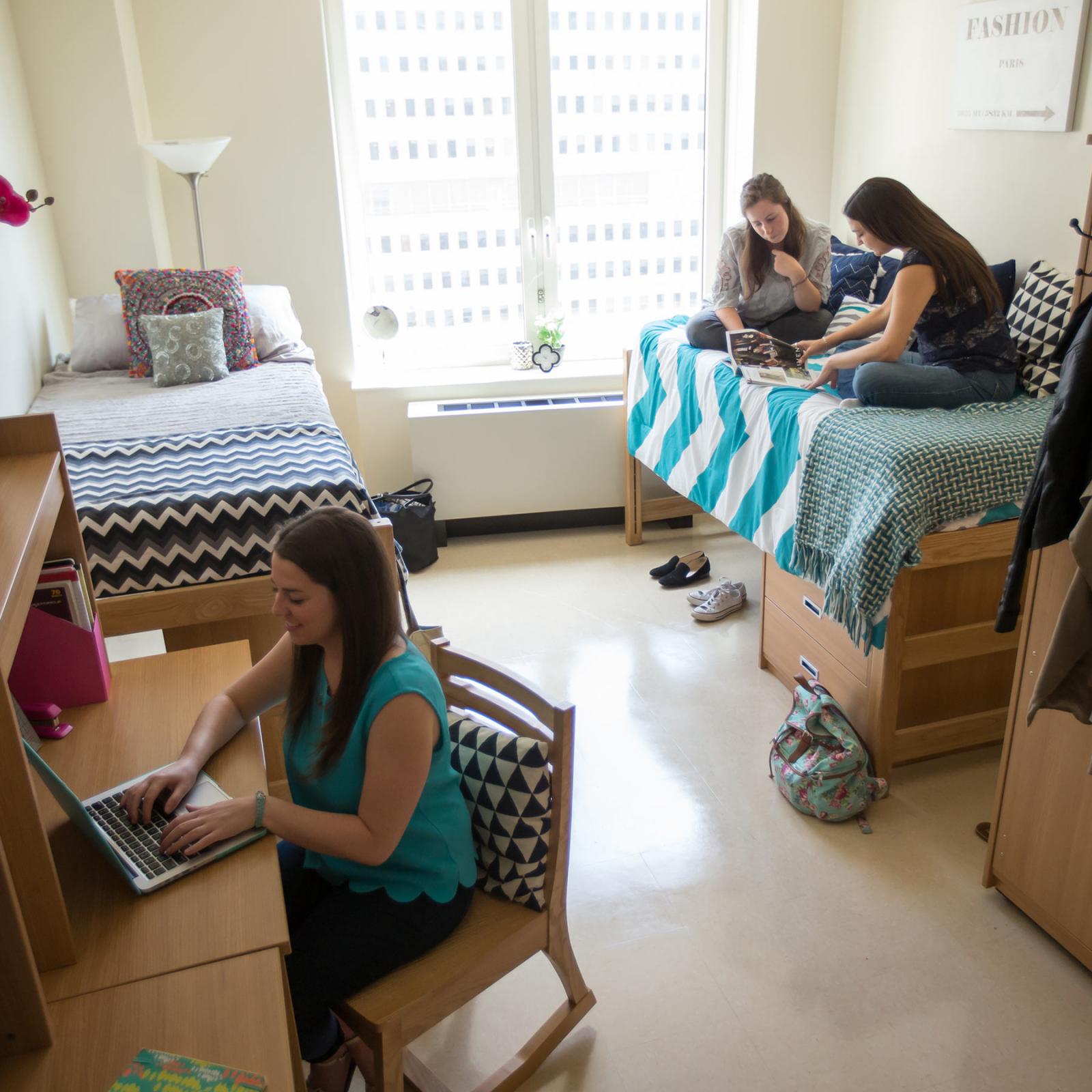 Students in a room in a residence hall studying and talking.