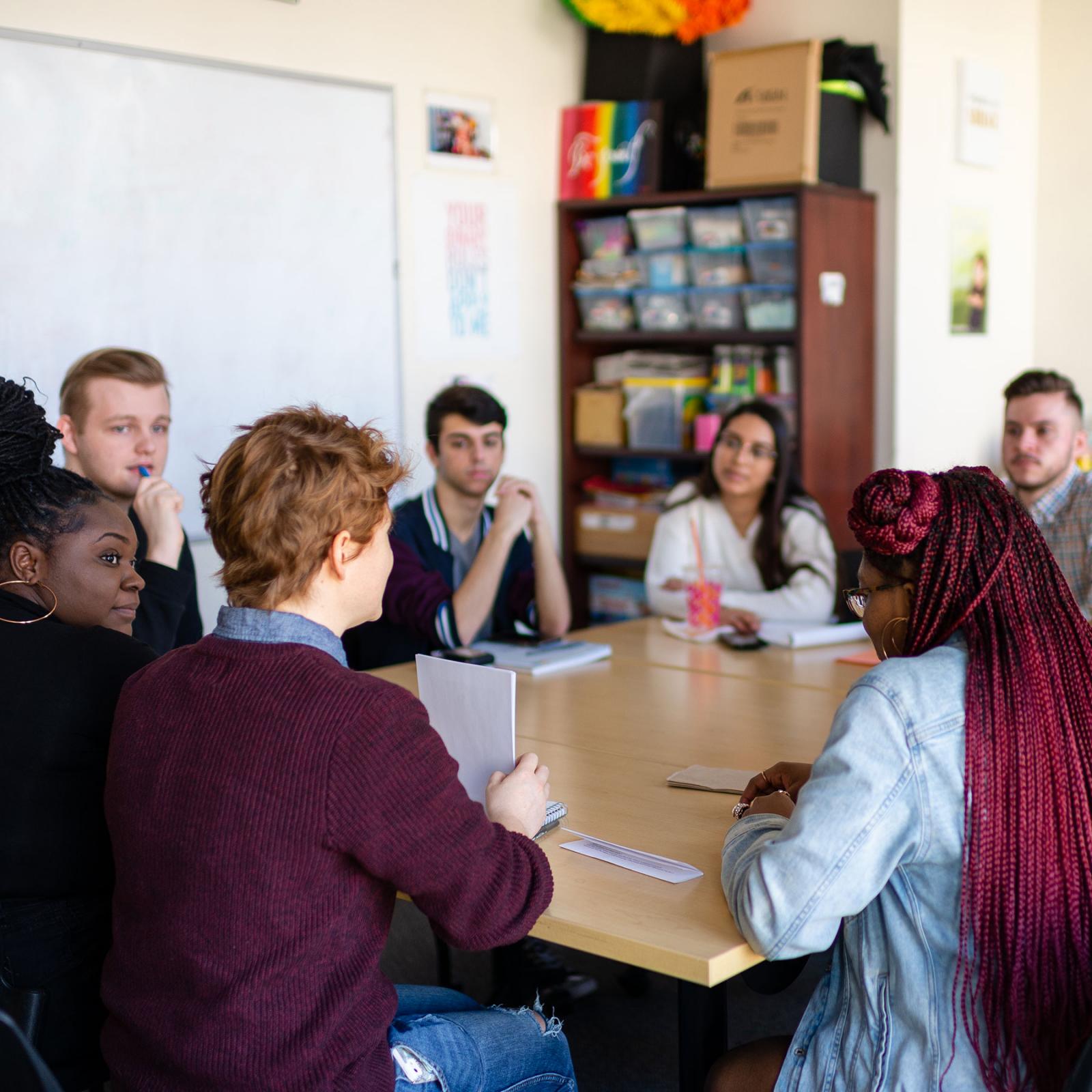 Group of students sitting around a table talking.