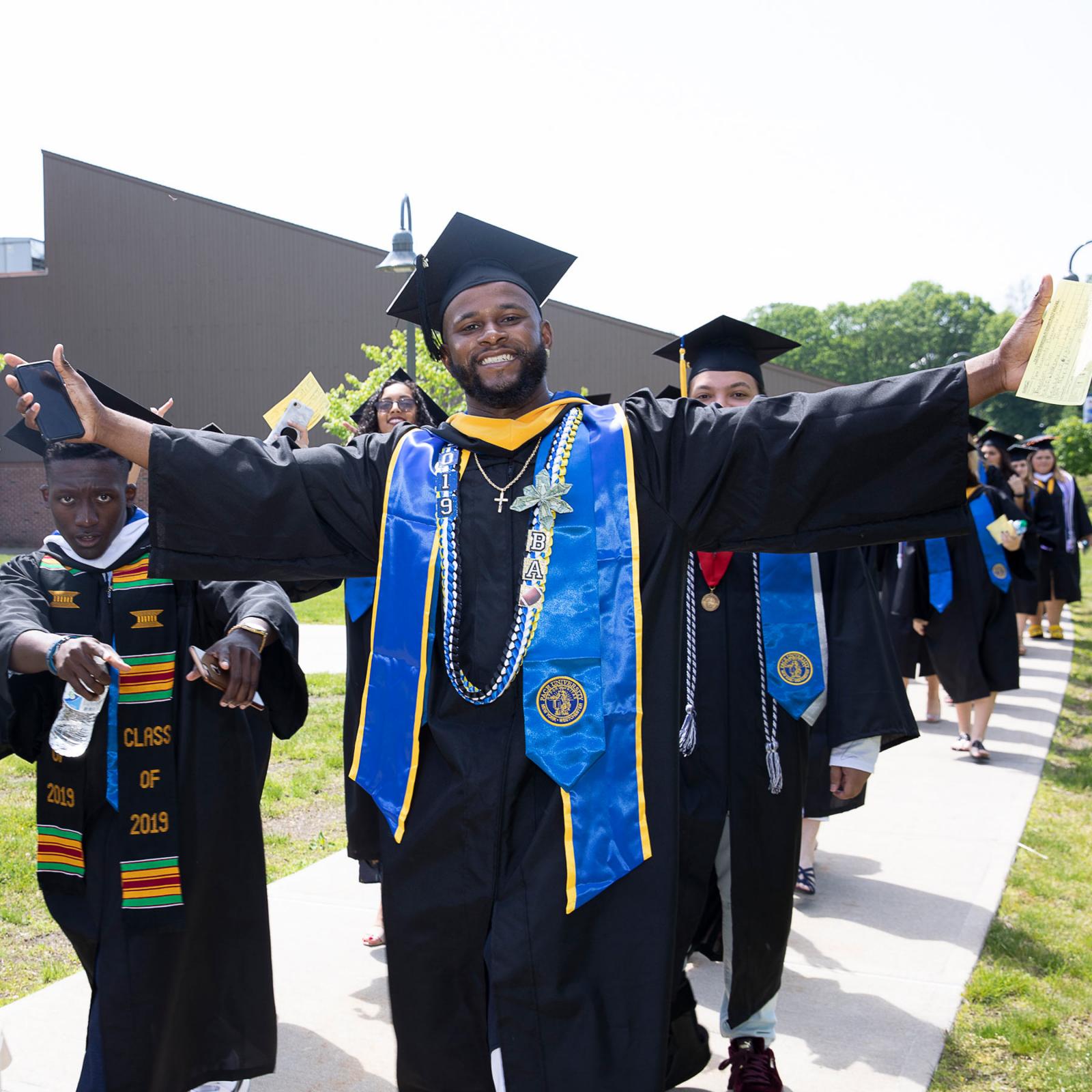 Student smiling at the camera wearing his cap and gown for his Commencement ceremony.