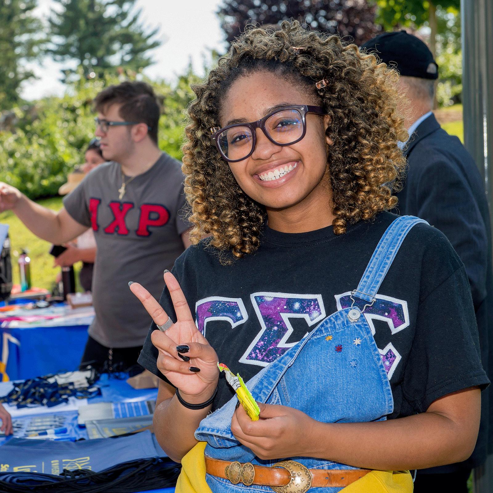 Student smiling at the camera making a peace sign