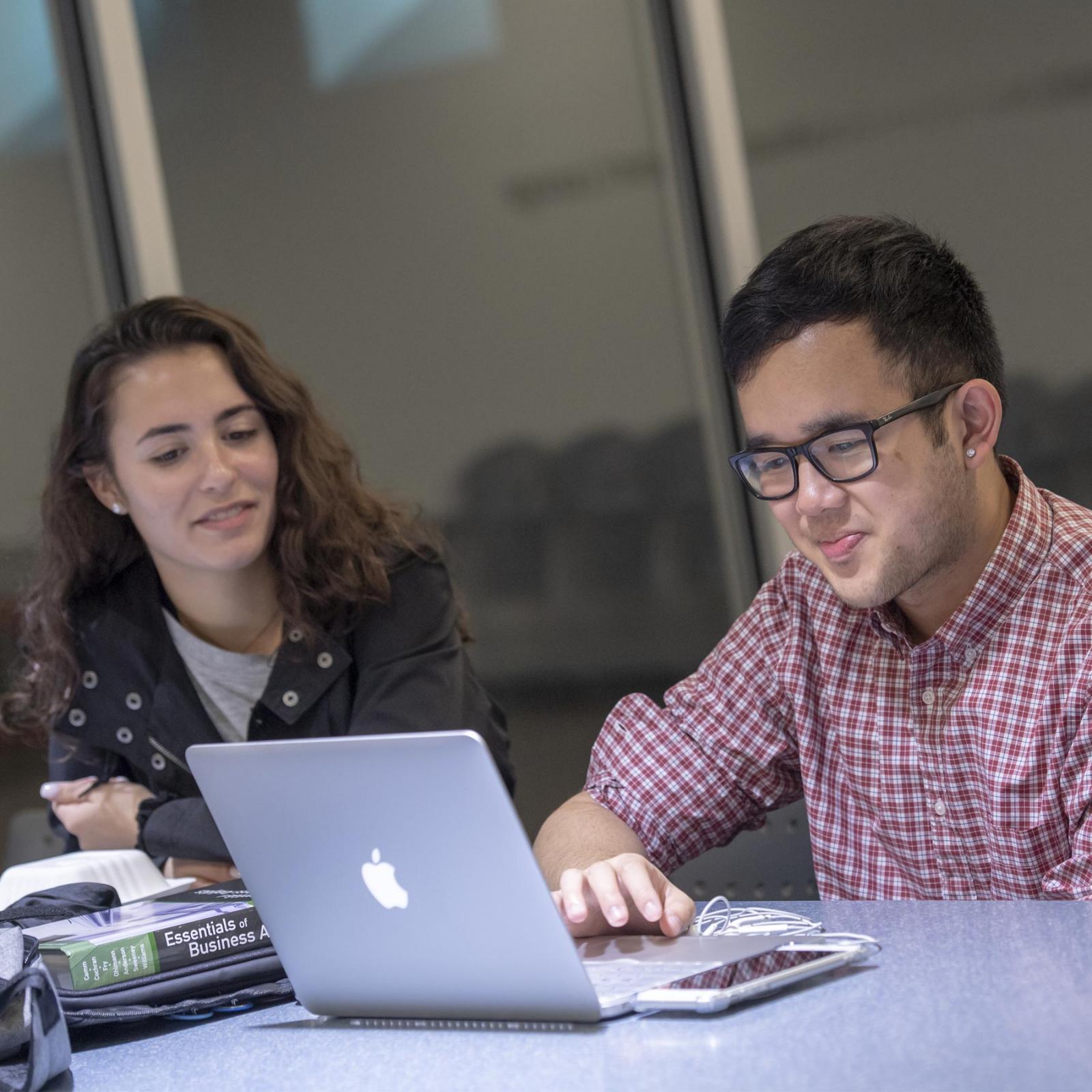 two students looking at a laptop