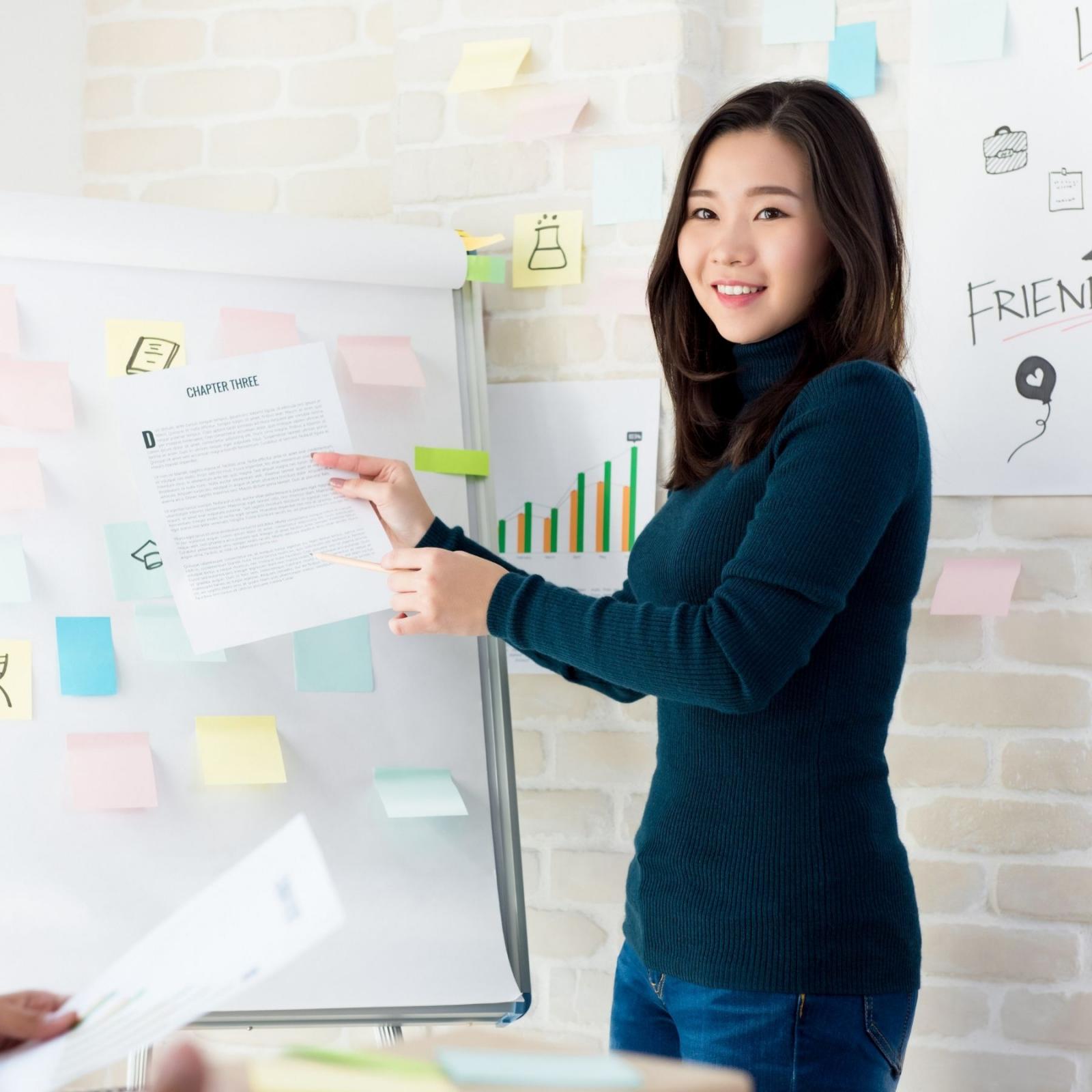 Asian female teacher showing a paper to her class smiling 