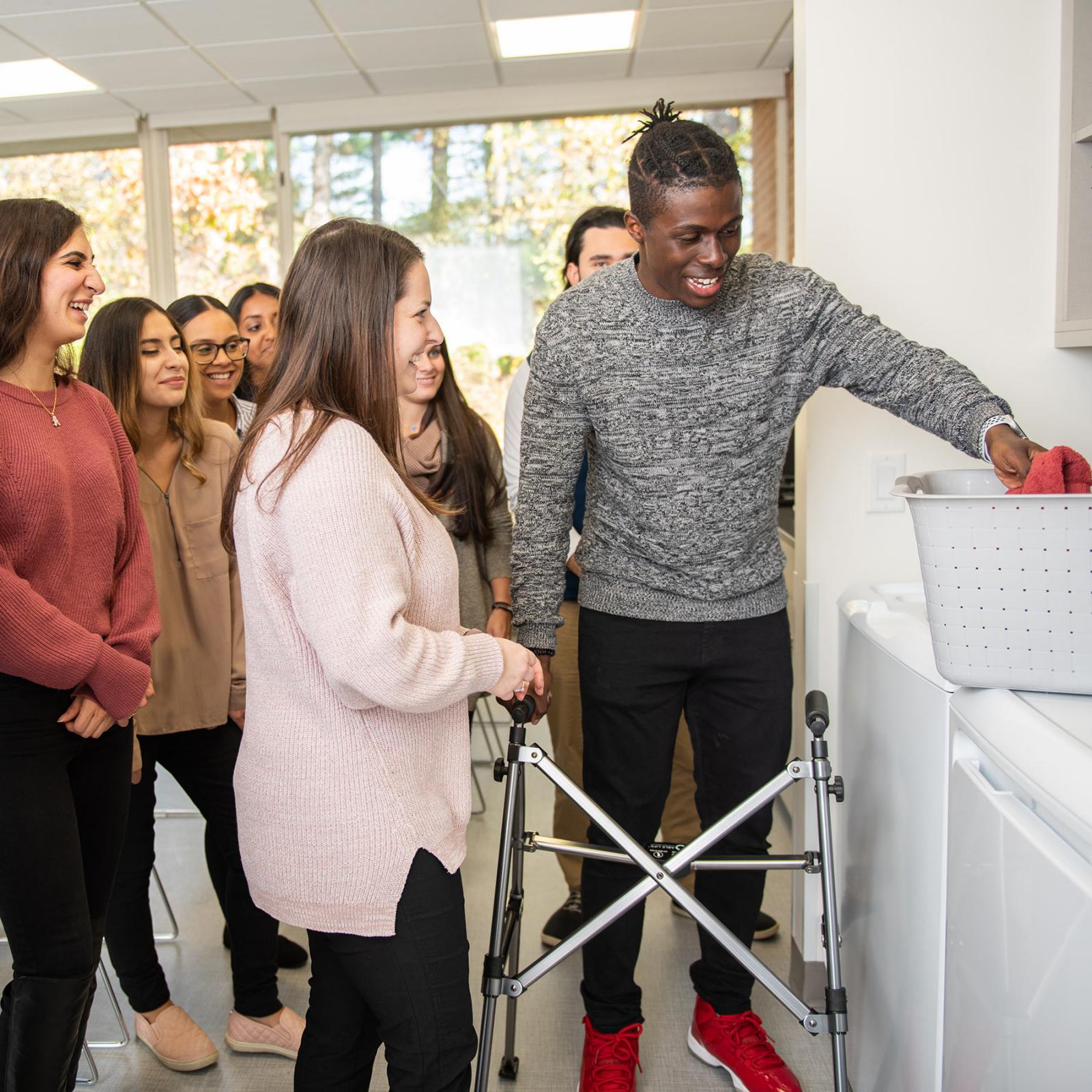 Students are helping a man with an injury to do the laundry.