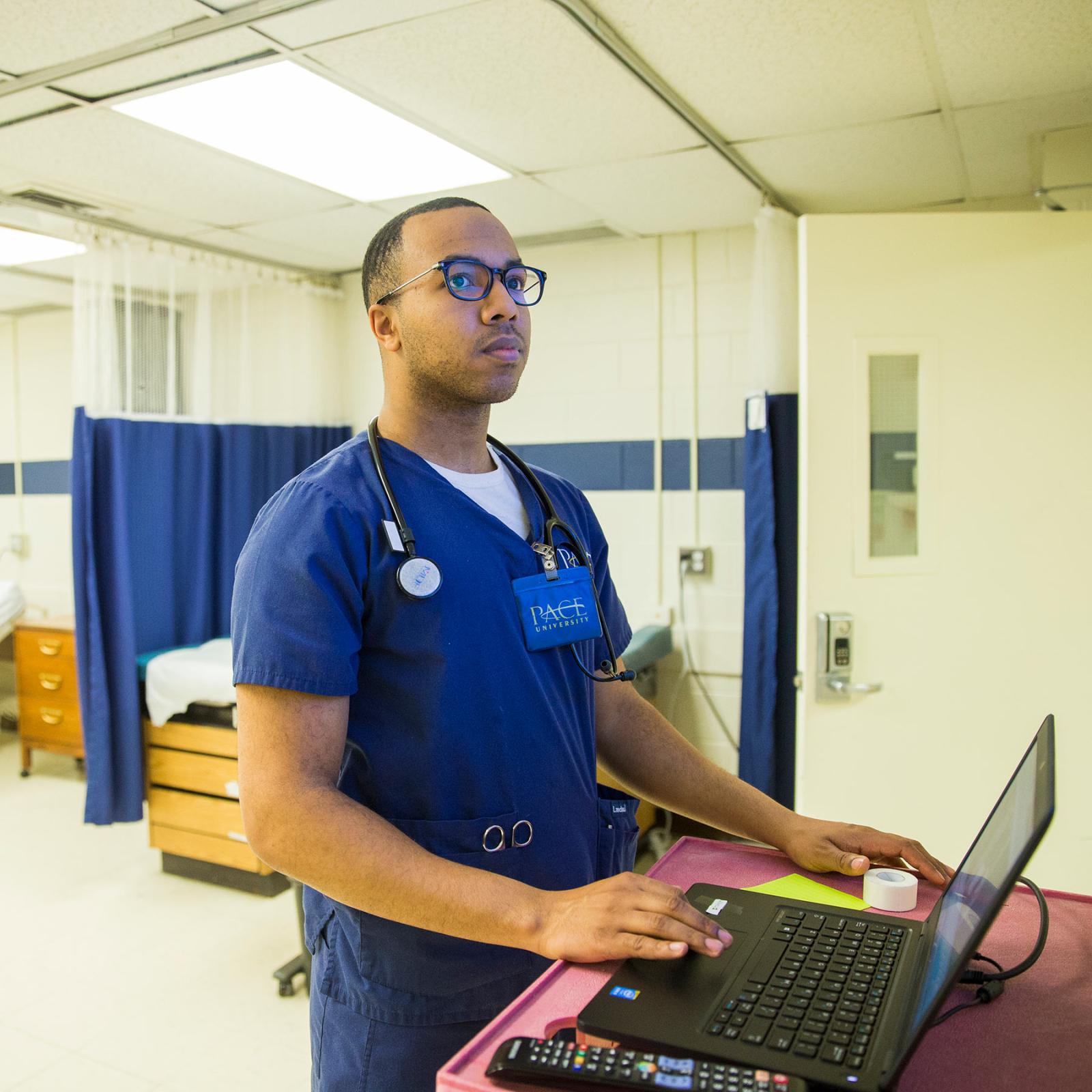 College of Health Professions student working on a computer in a clinical setting.
