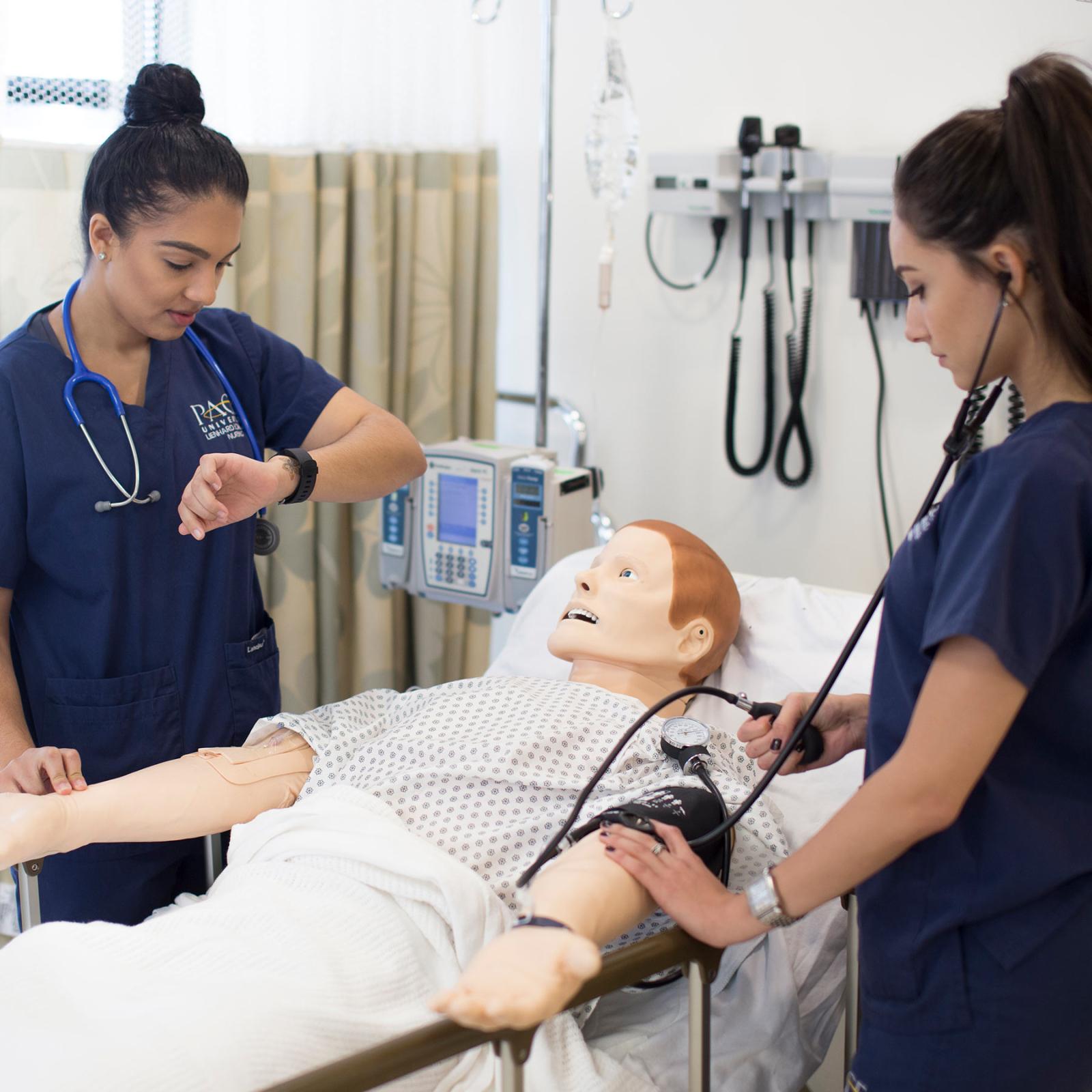 Two nursing students woking on a manikin in the simulation lab.