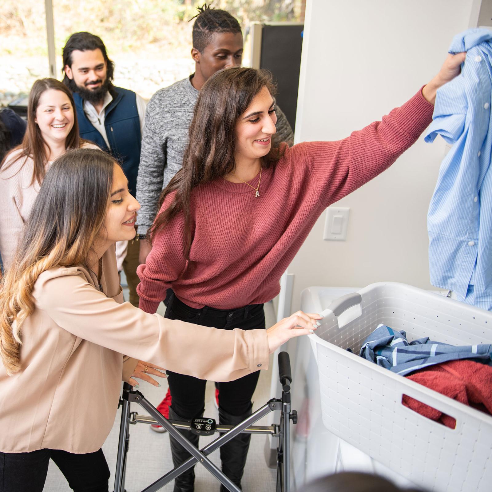 CHP Students helping another student do the laundry in an occupational therapy setting.