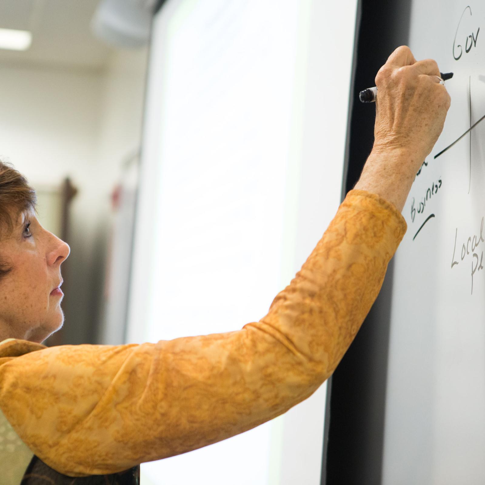 management professor Claudia Green writing on a whiteboard