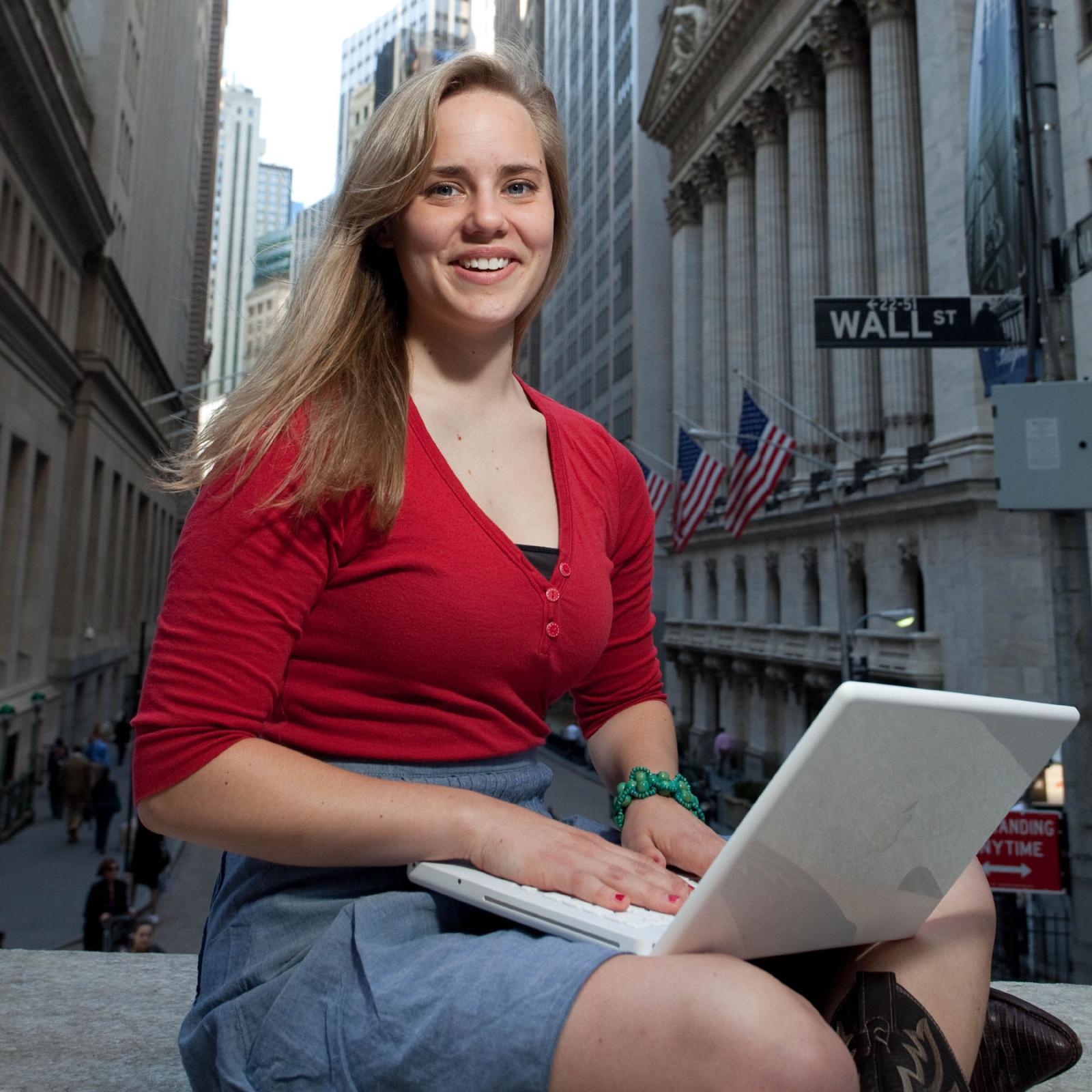 Lubin student sitting with laptop on Wall Street near the New York City Campus