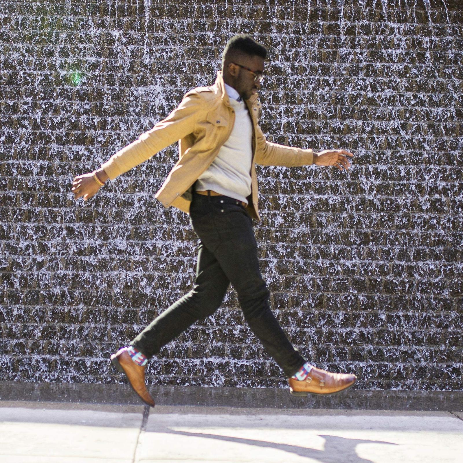 Male Pace University student leaping in the air, near the New York City campus