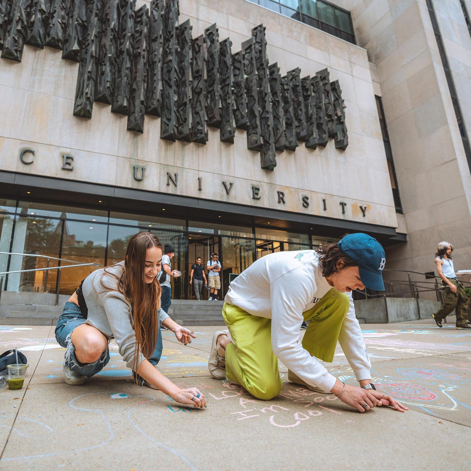 two students chalking in the front of One Pace Plaza
