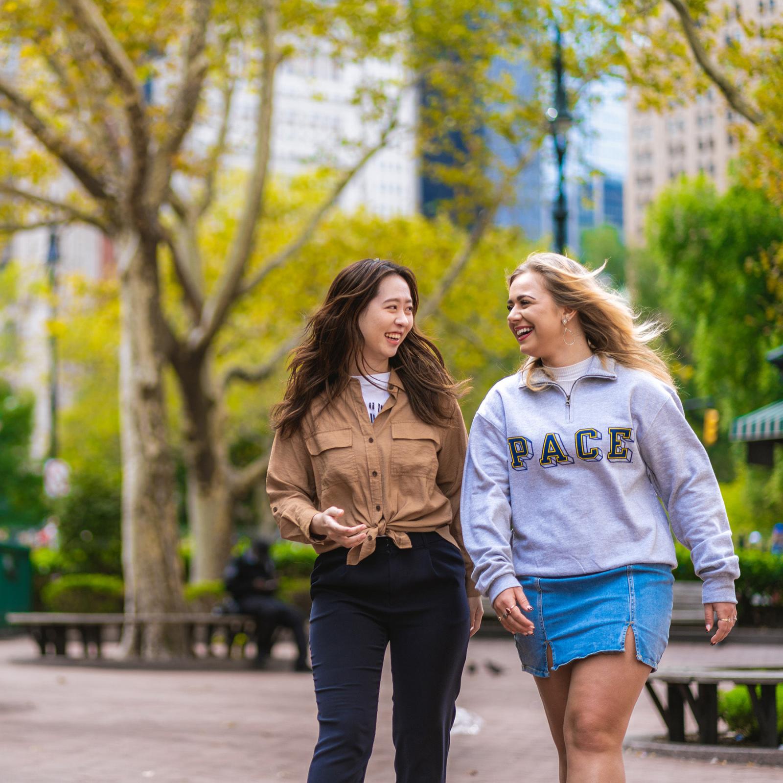 two Pace University students walk through a park near the NYC campus