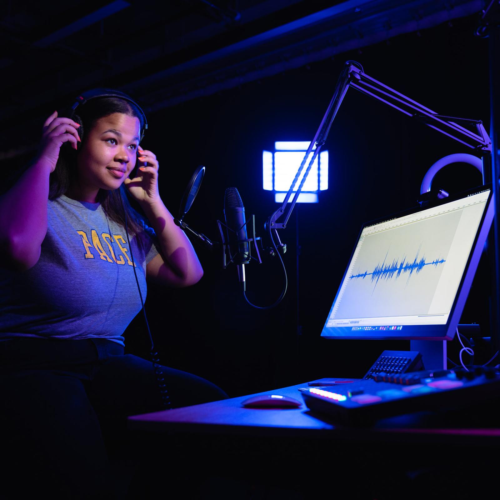 a Pace student puts headphones on in a recording studio