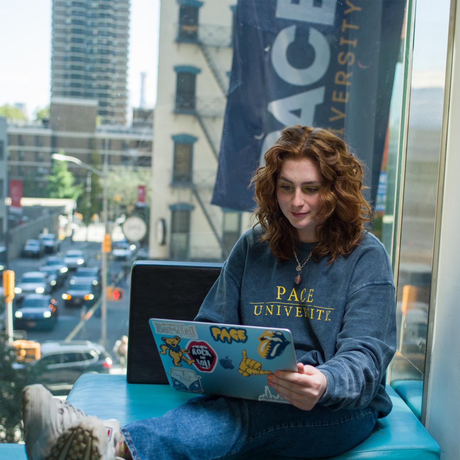 Pace student reading something on her laptop. 