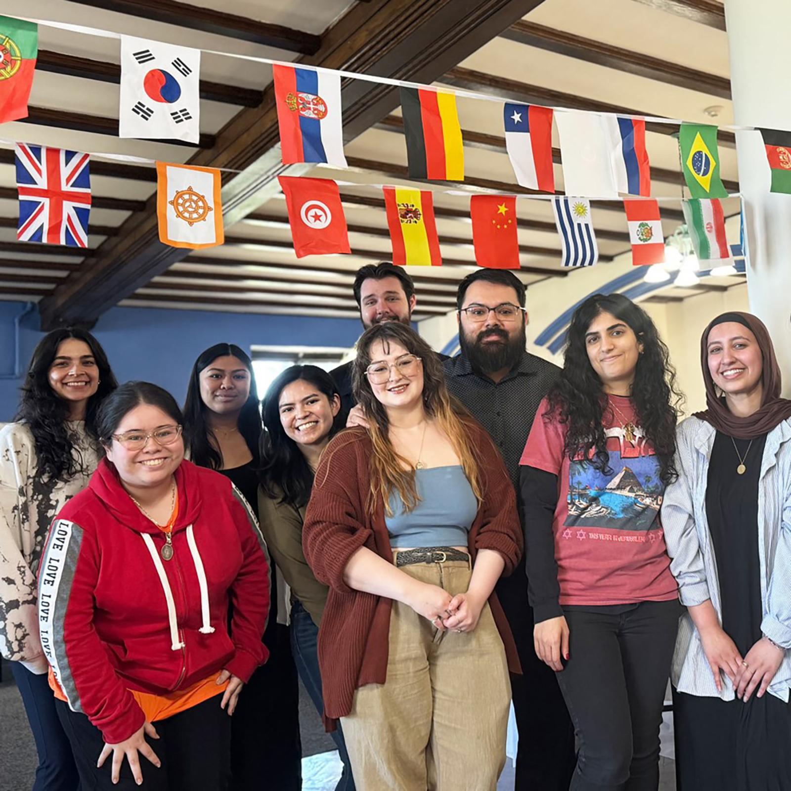 Students posing below a number of international flags