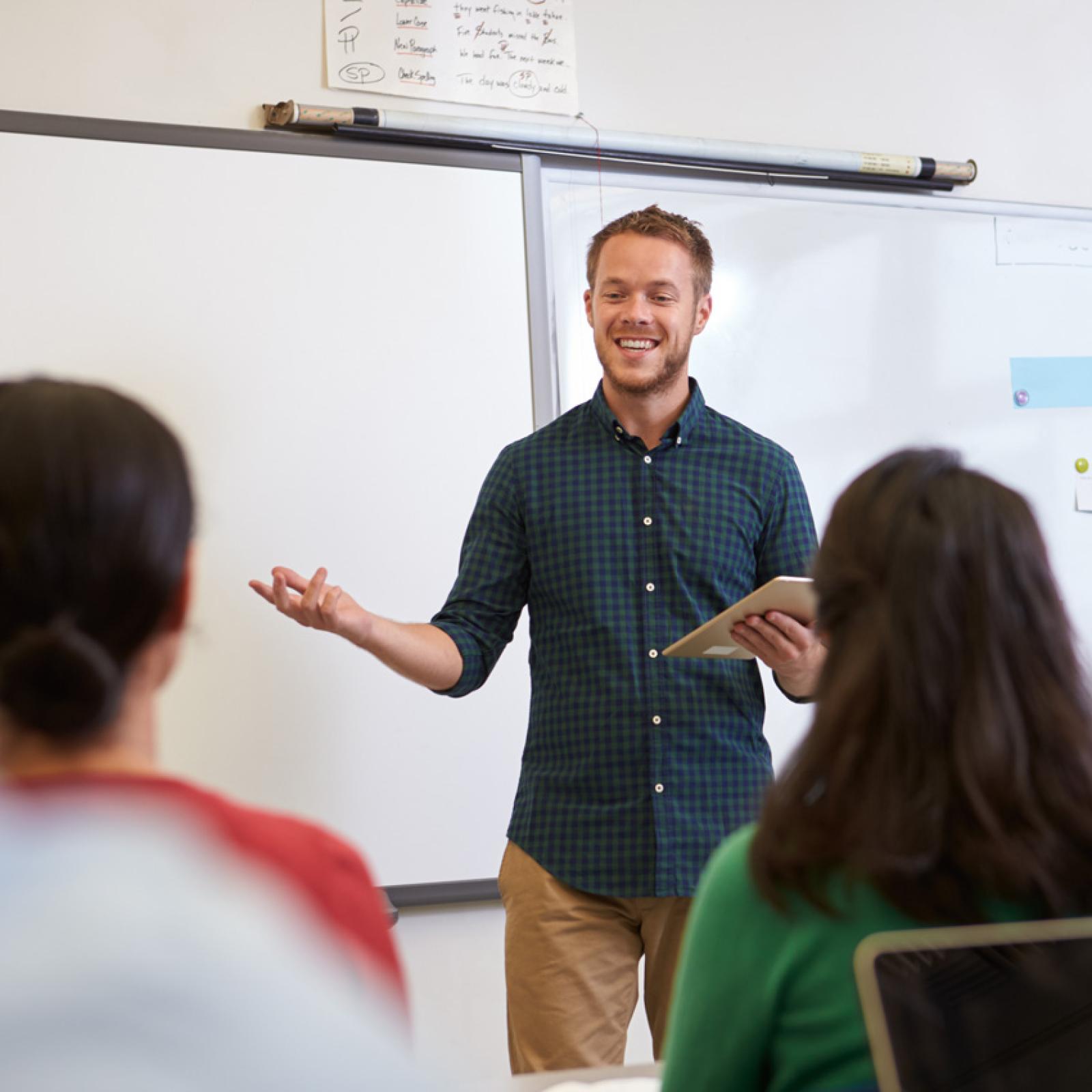 A young man in front of a classroom at Pace University.