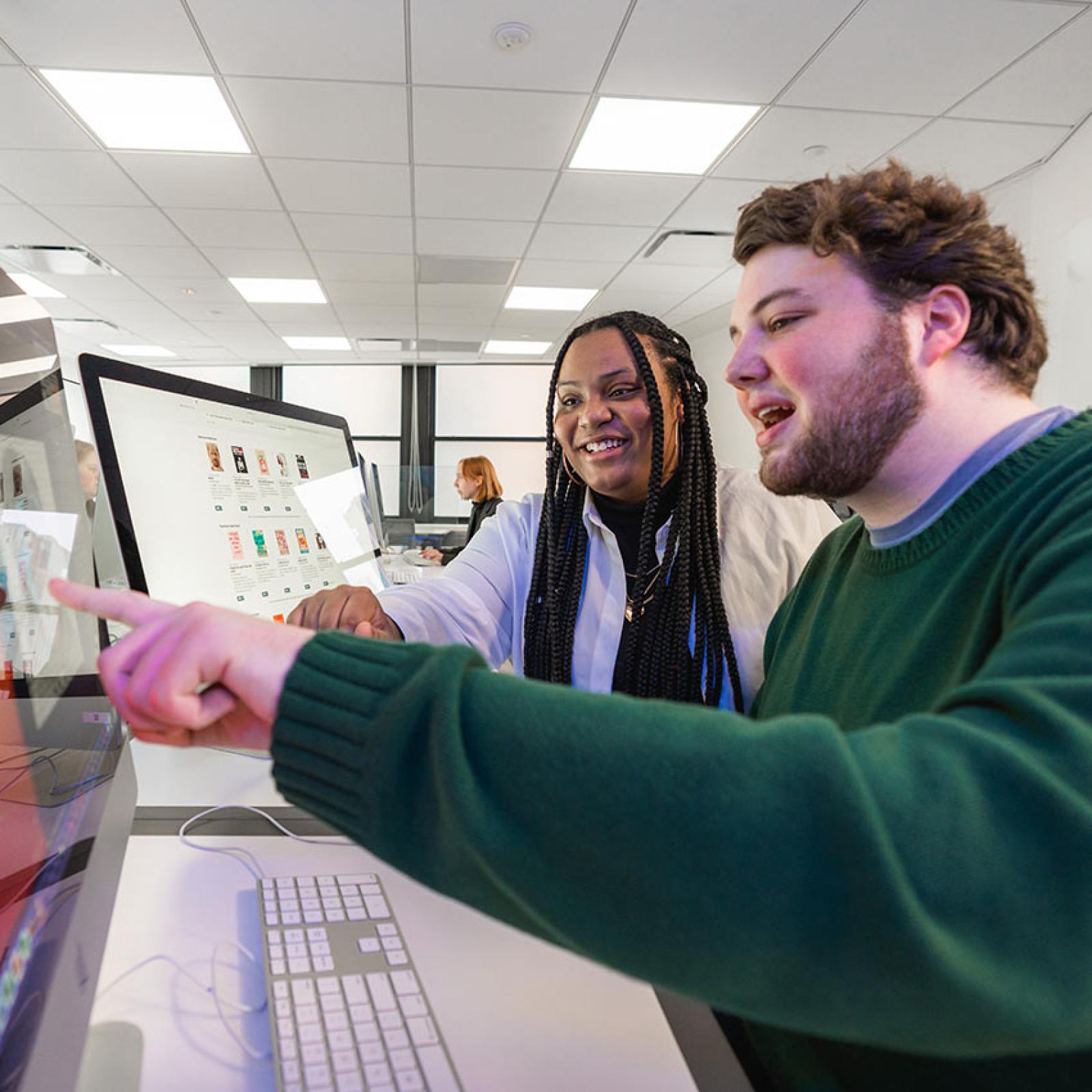 Two Pace University students work together on a computer screen