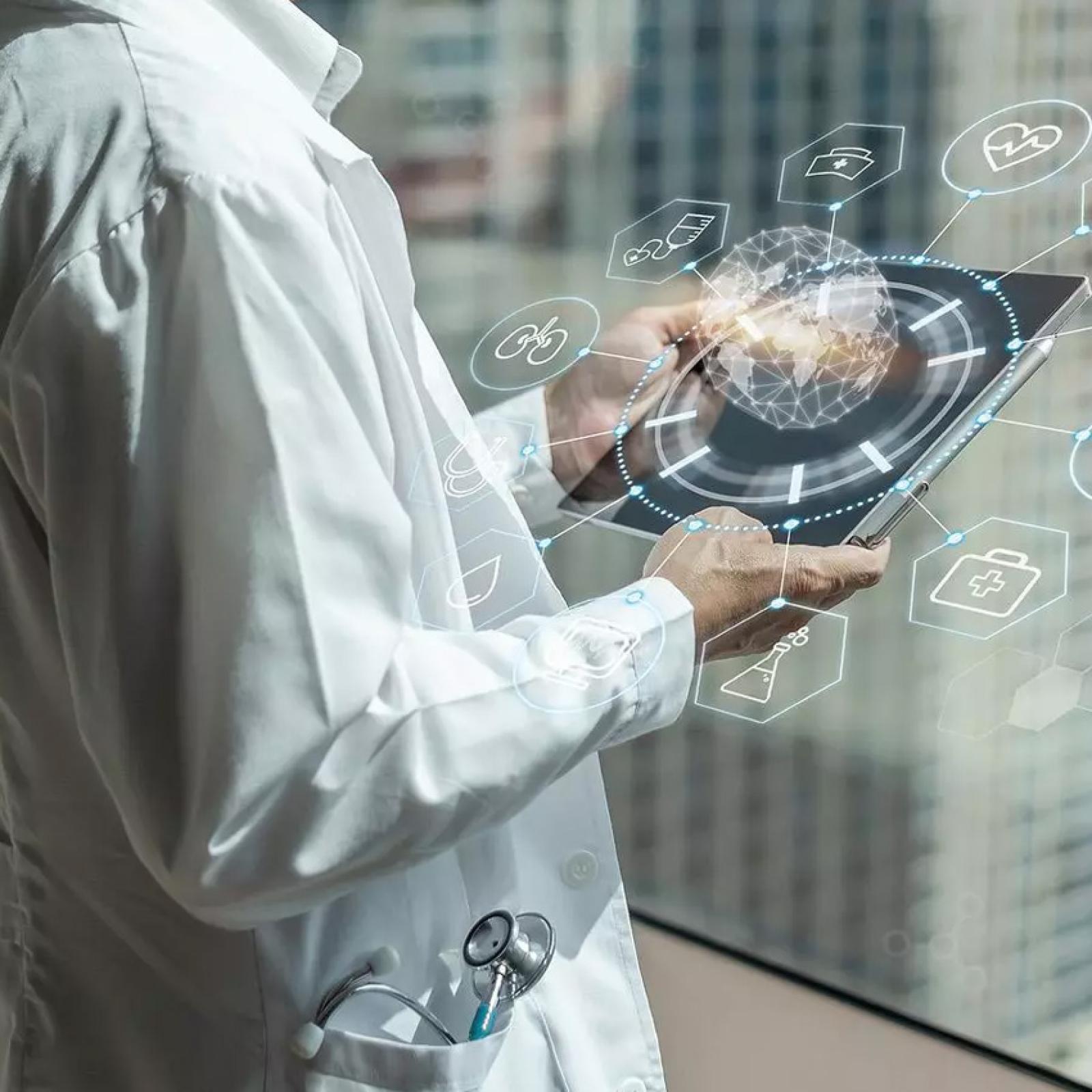A person in a white labcoat holding a tablet with medical designs. 