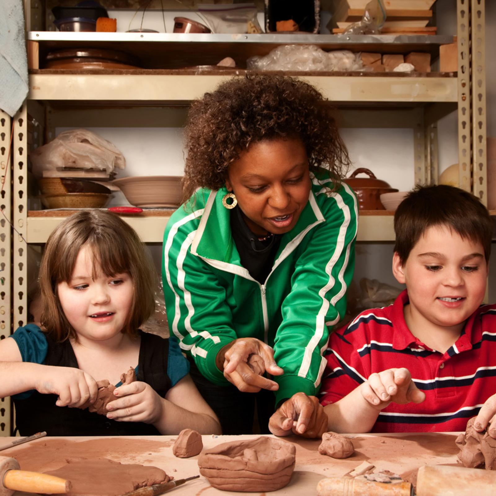 A teacher working on a clay project with young students.