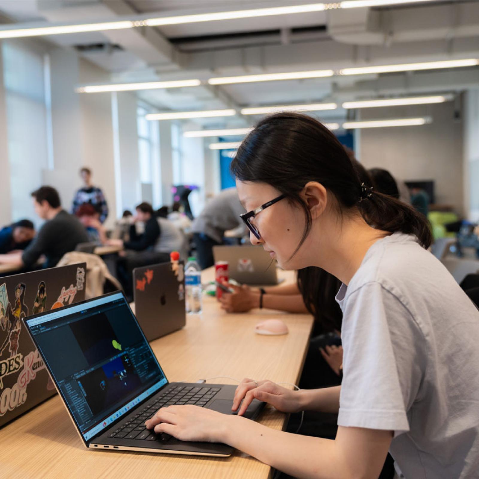 Woman working on a laptop in a Pace University computer science area.
