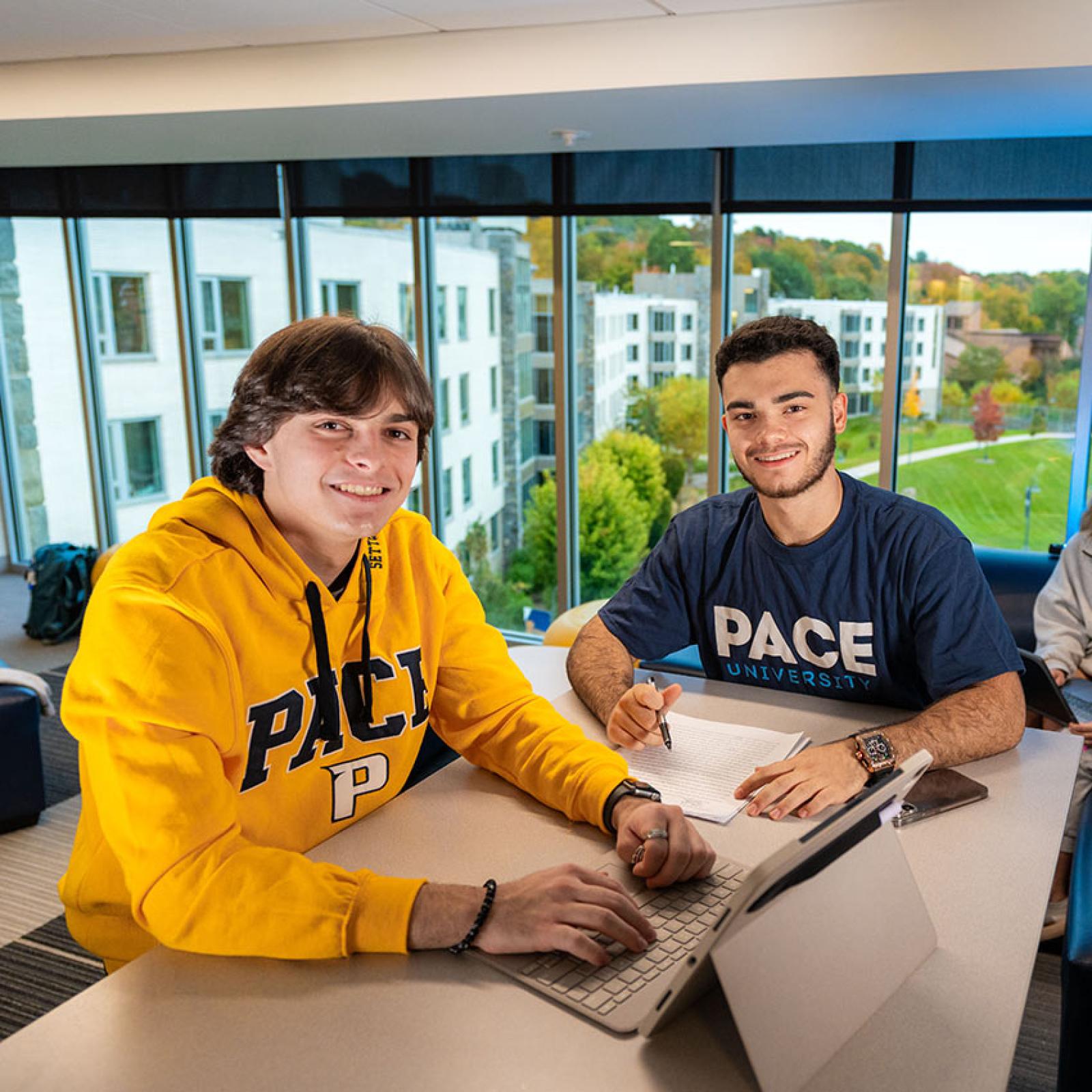 Two Pace students sit at an iPad and smile