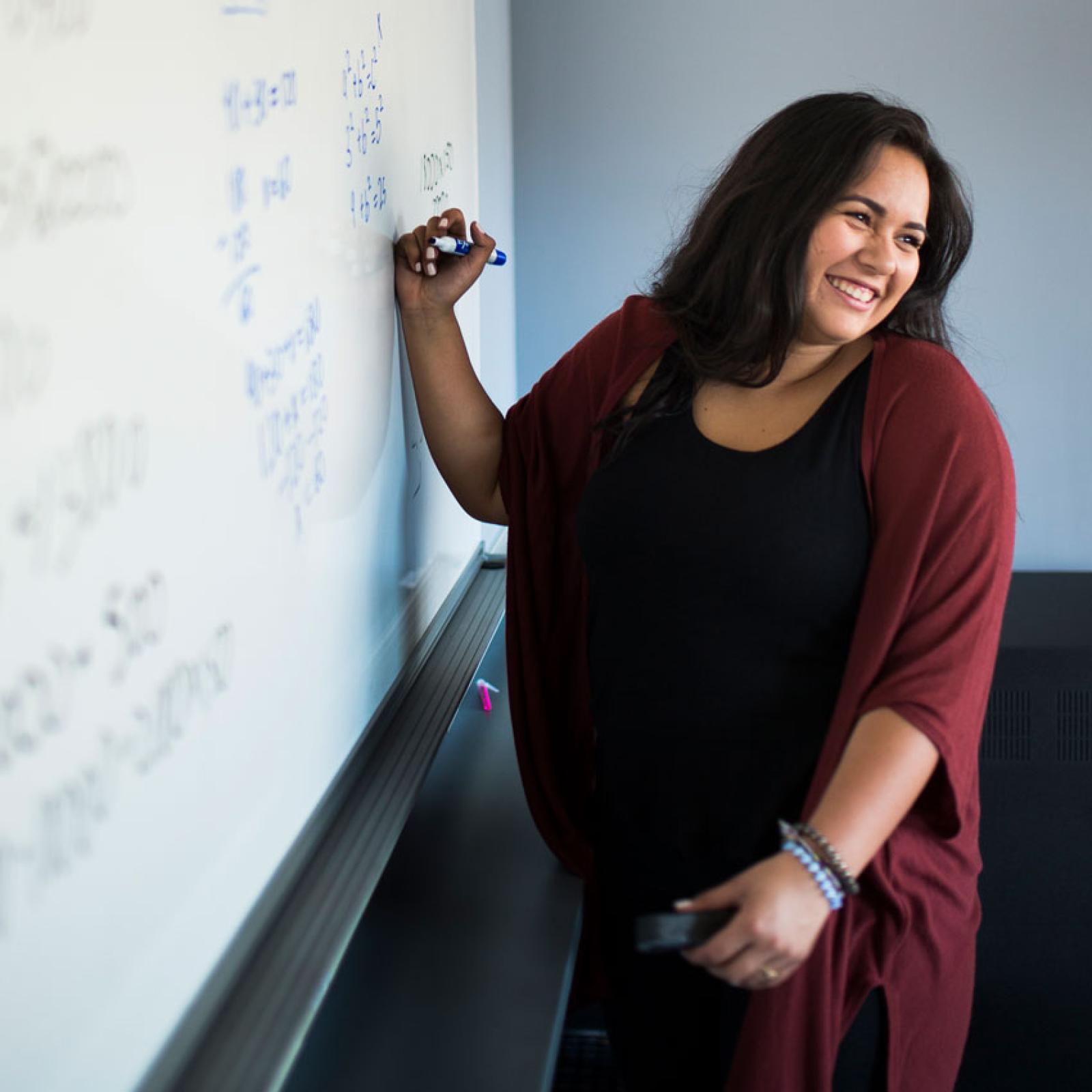 A Pace student doing math equations on a white board.