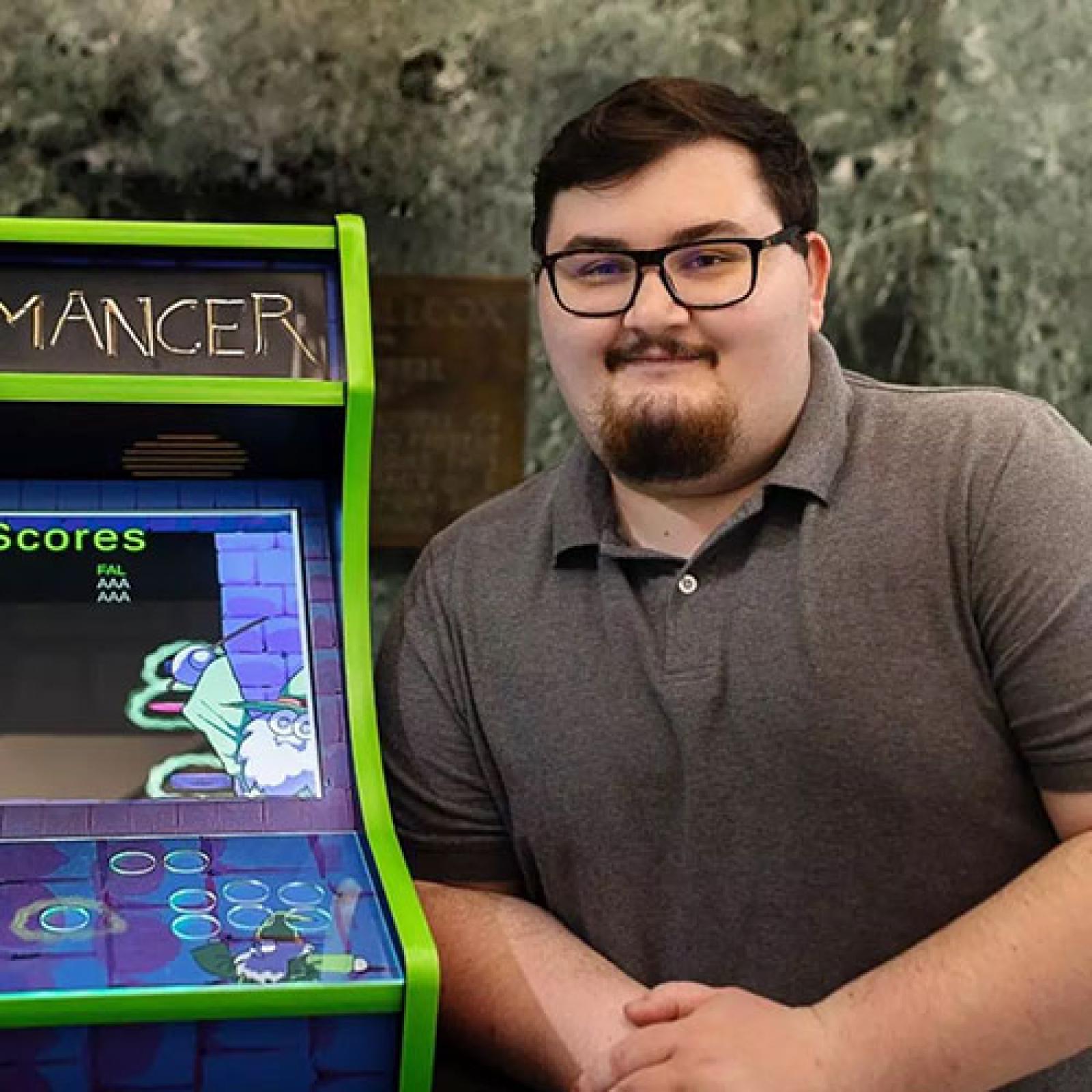 Pace University student Michael Falco posing with his arcade game.
