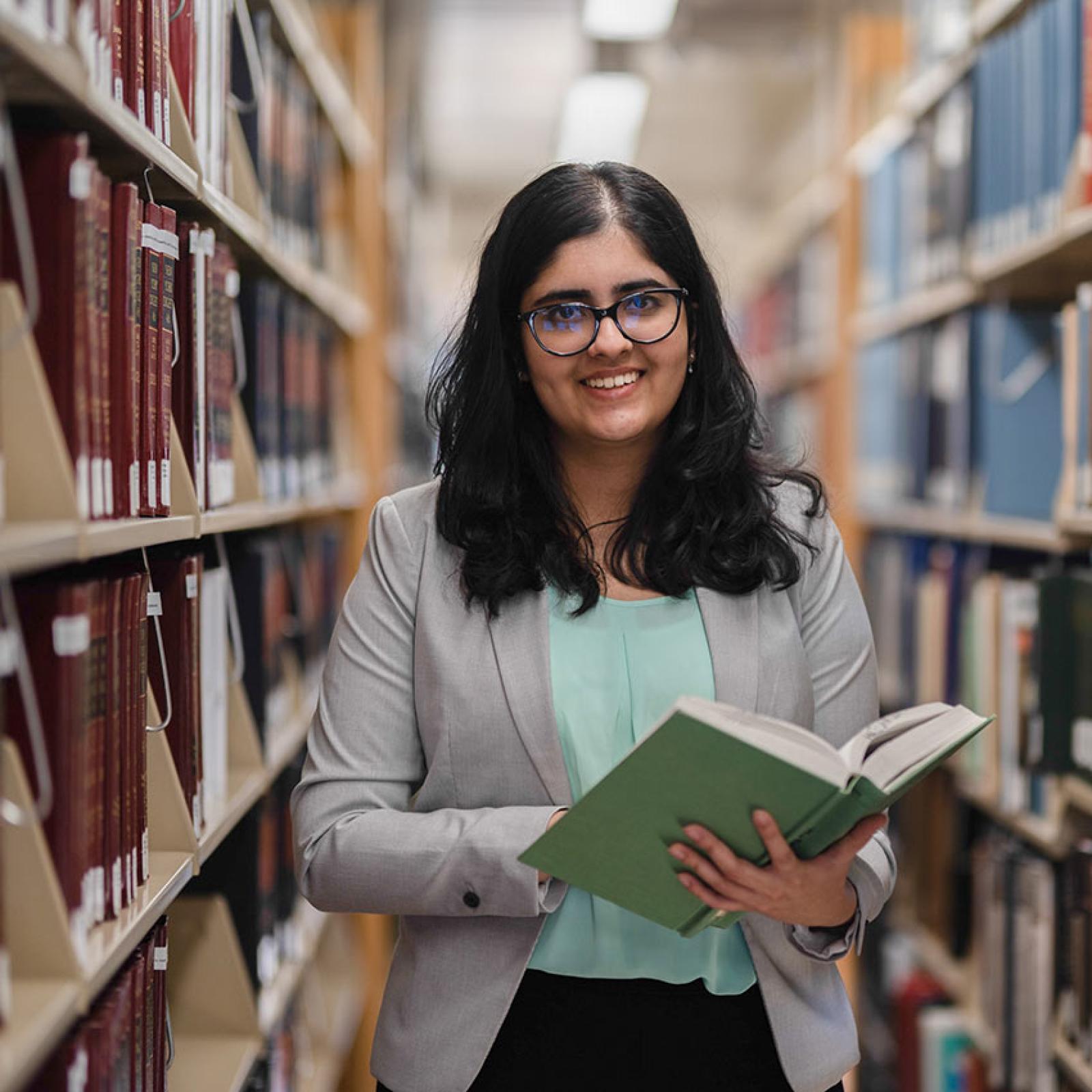 A Pace University student holds a book in the library