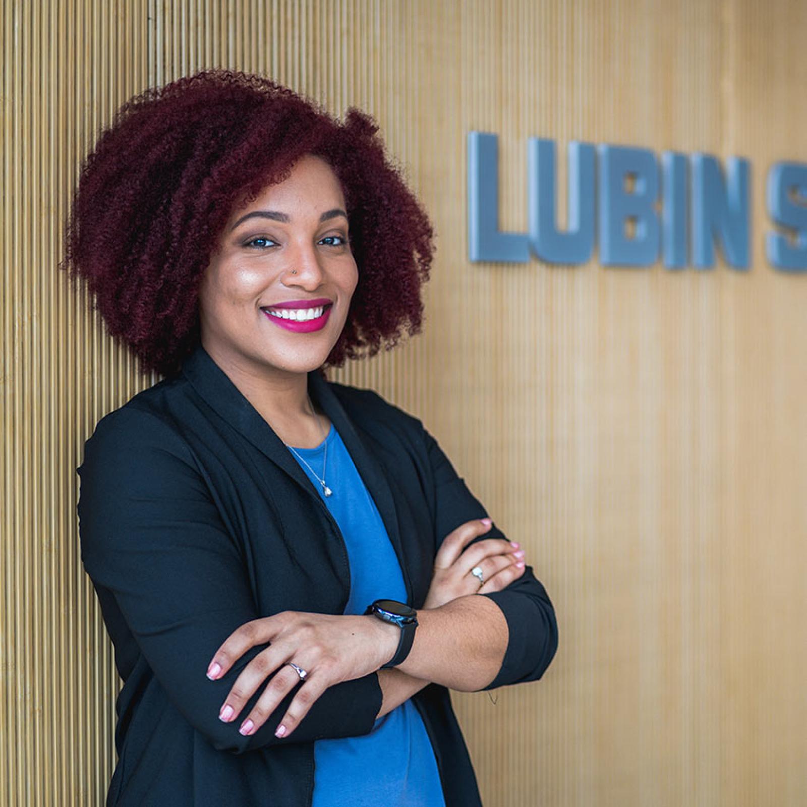 A Pace University student leans against a wall that says Lubin