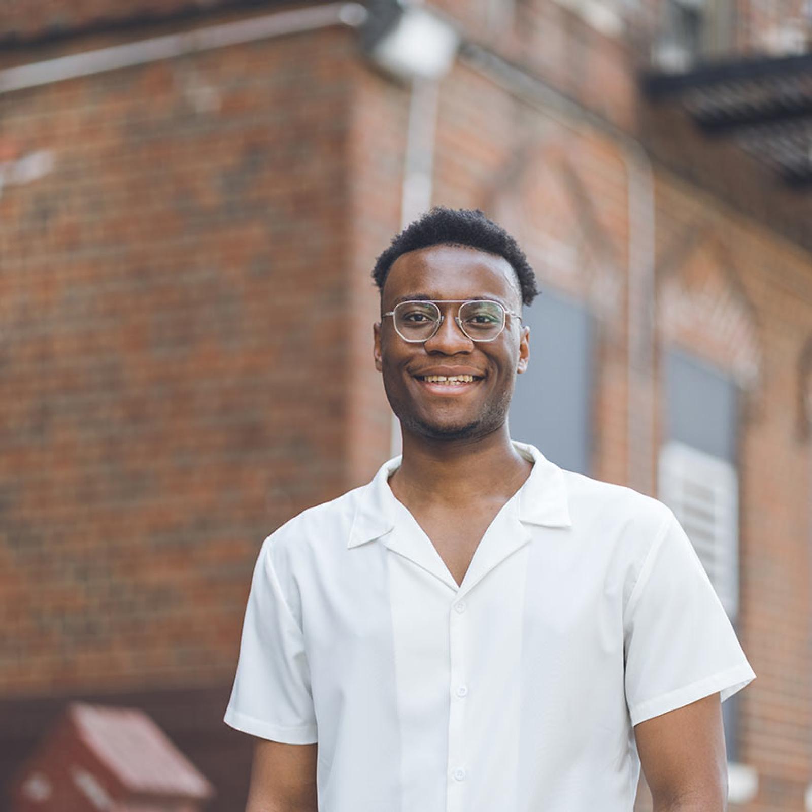 A Pace student stands in front of a brick building