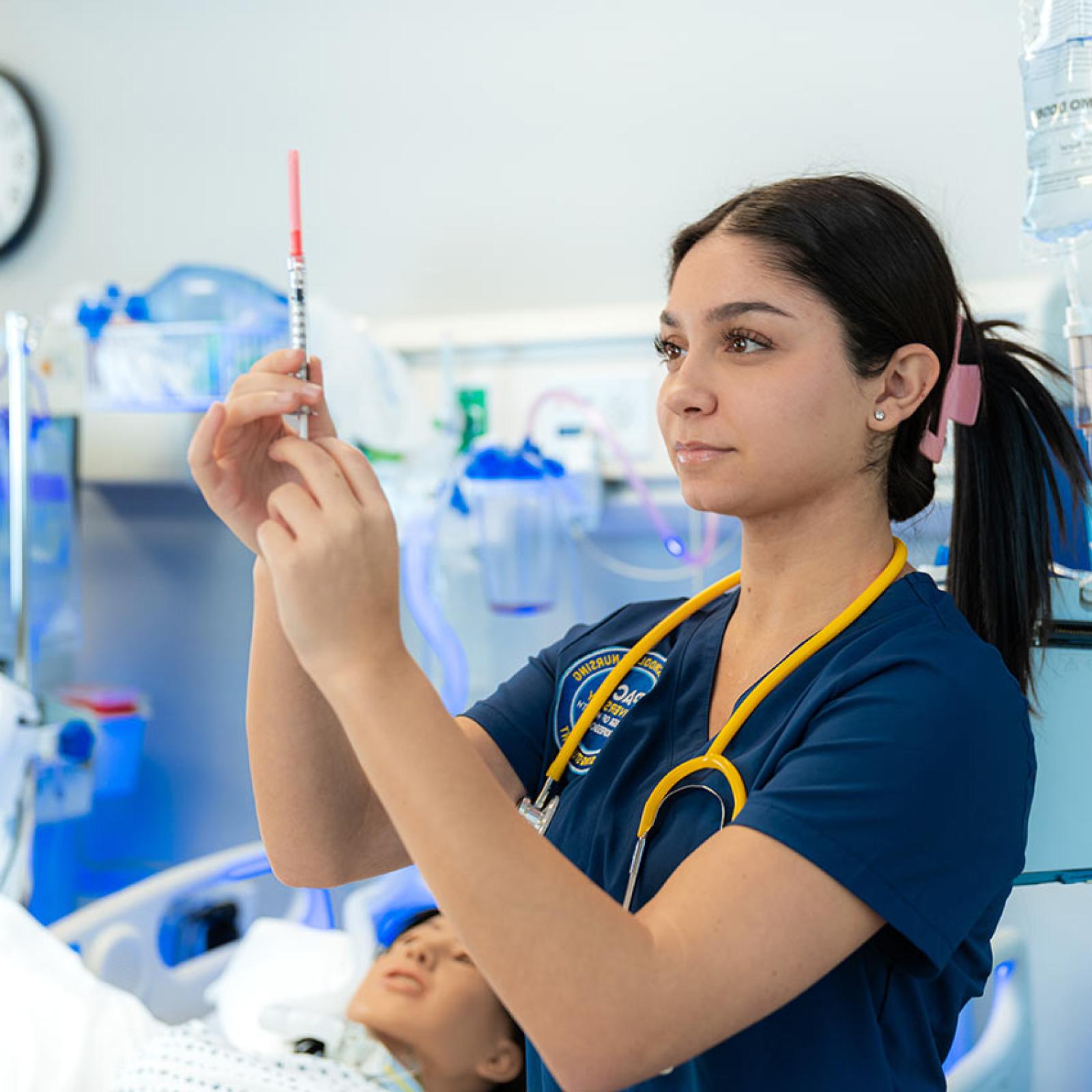 A Pace University medical student looks at a syringe.